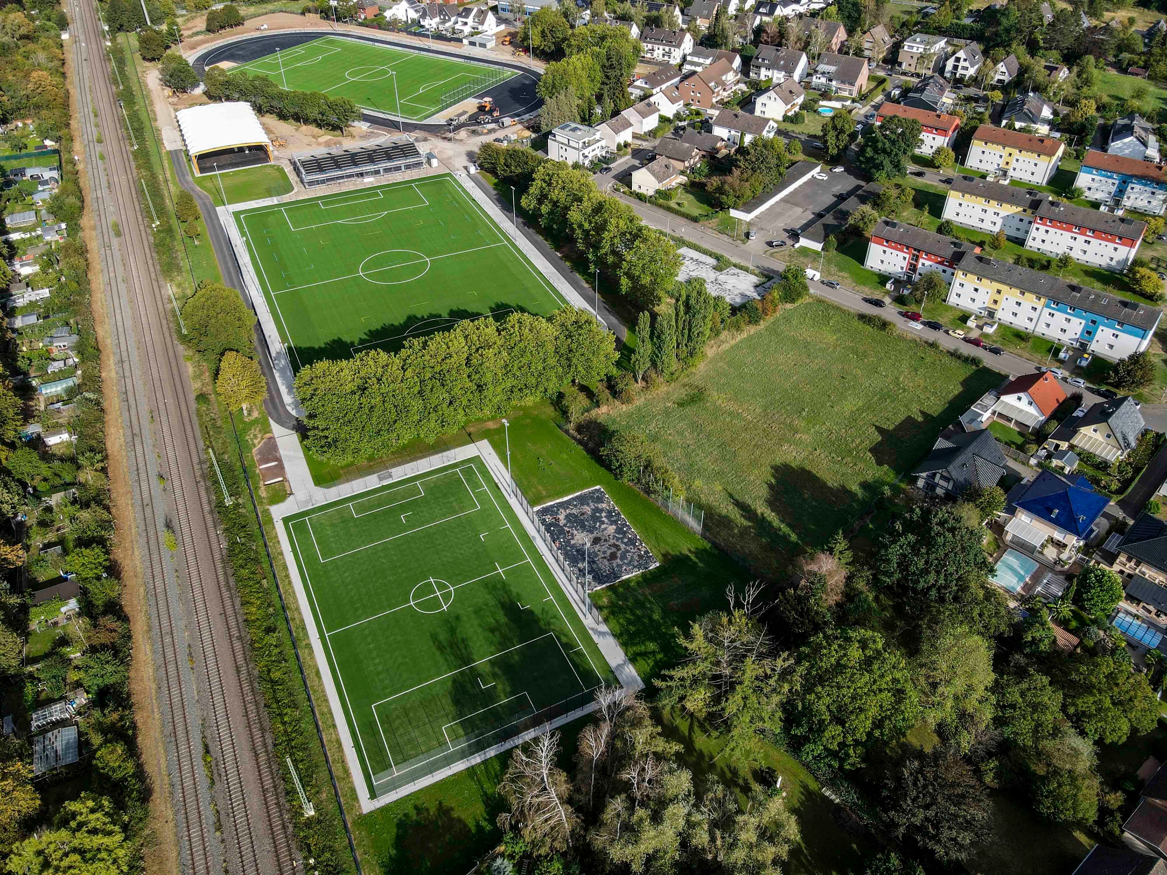Das Luftbild zeigt die Anlage mit drei Kunstrasenfußballfeldern, mehreren Gebäuden und einem Beachvolleyballplatz.