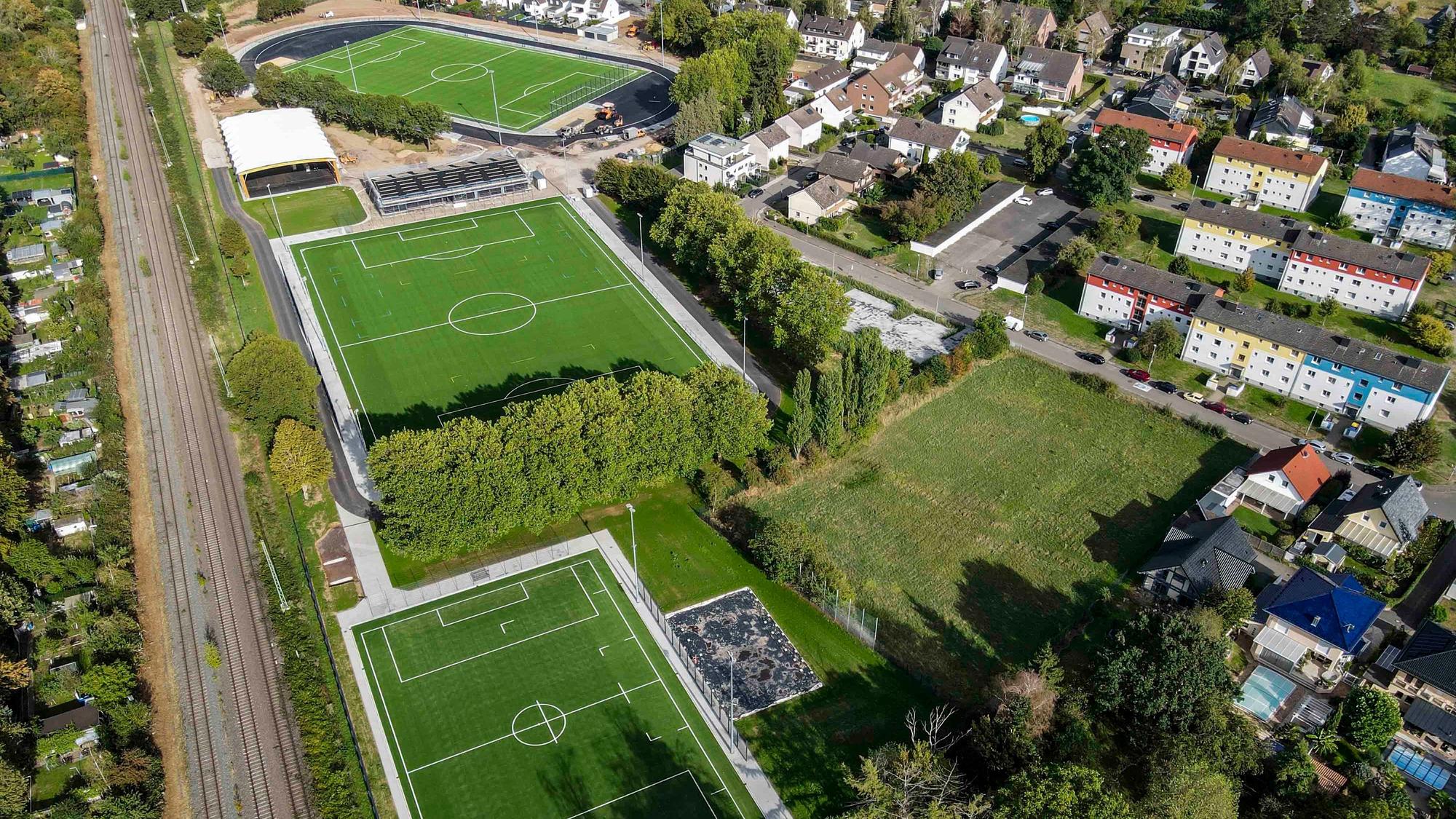 Das Luftbild zeigt die Anlage mit drei Kunstrasenfußballfeldern, mehreren Gebäuden und einem Beachvolleyballplatz.