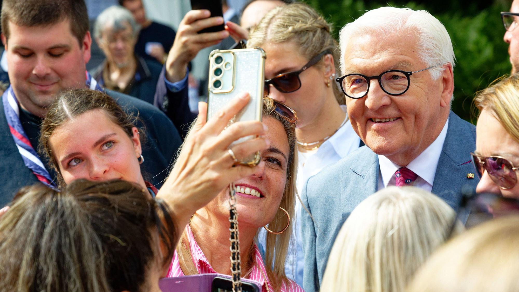 Bundespräsident Frank-Walter Steinmeier (r) macht beim Bürgerfest im Park der Villa Hammerschmidt in Bonn Selfies mit Besuchern.
