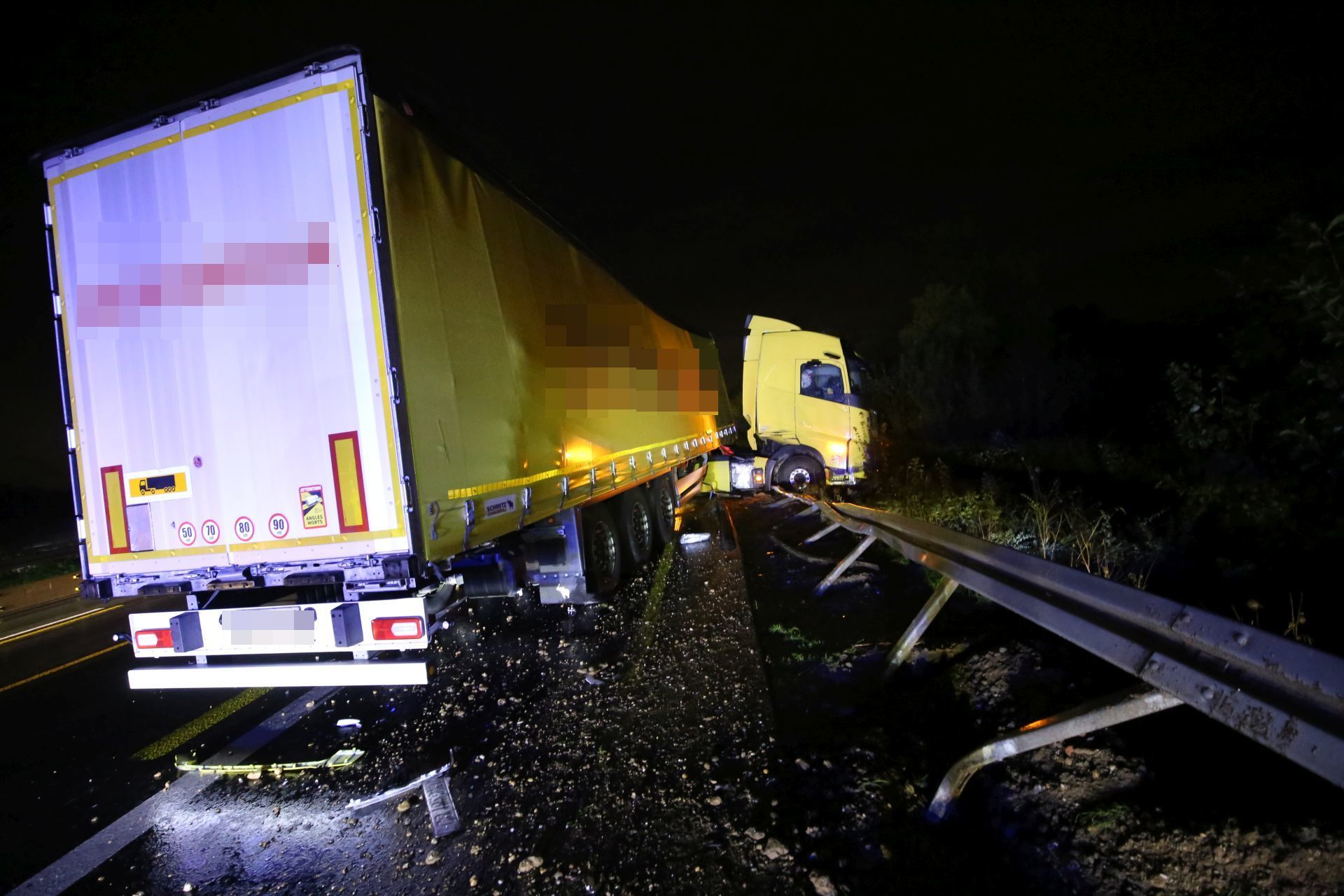 Ein Sattelzug mit gelbem Führerhaus hat die Leitplanke an der Autobahn durchbrochen.