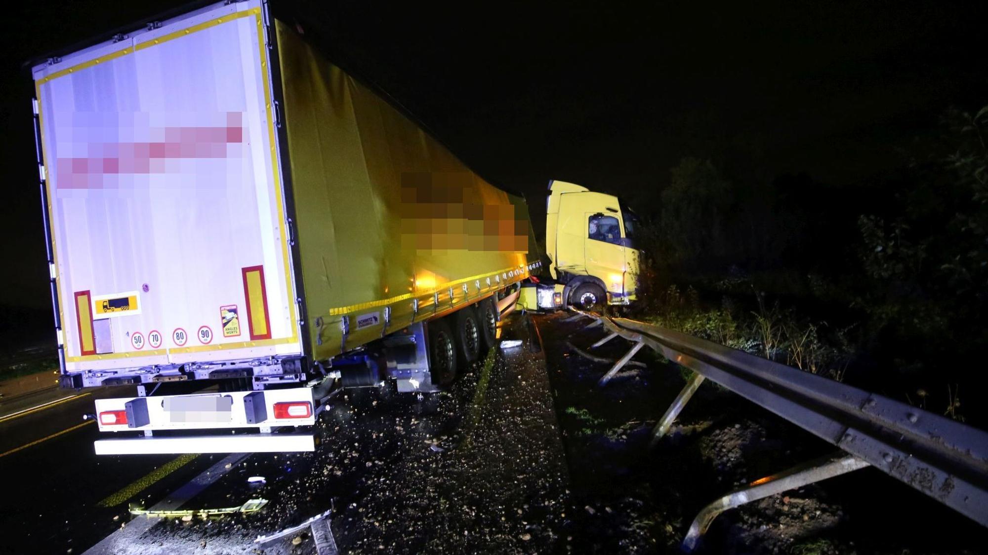 Ein Sattelzug mit gelbem Führerhaus hat die Leitplanke an der Autobahn durchbrochen.