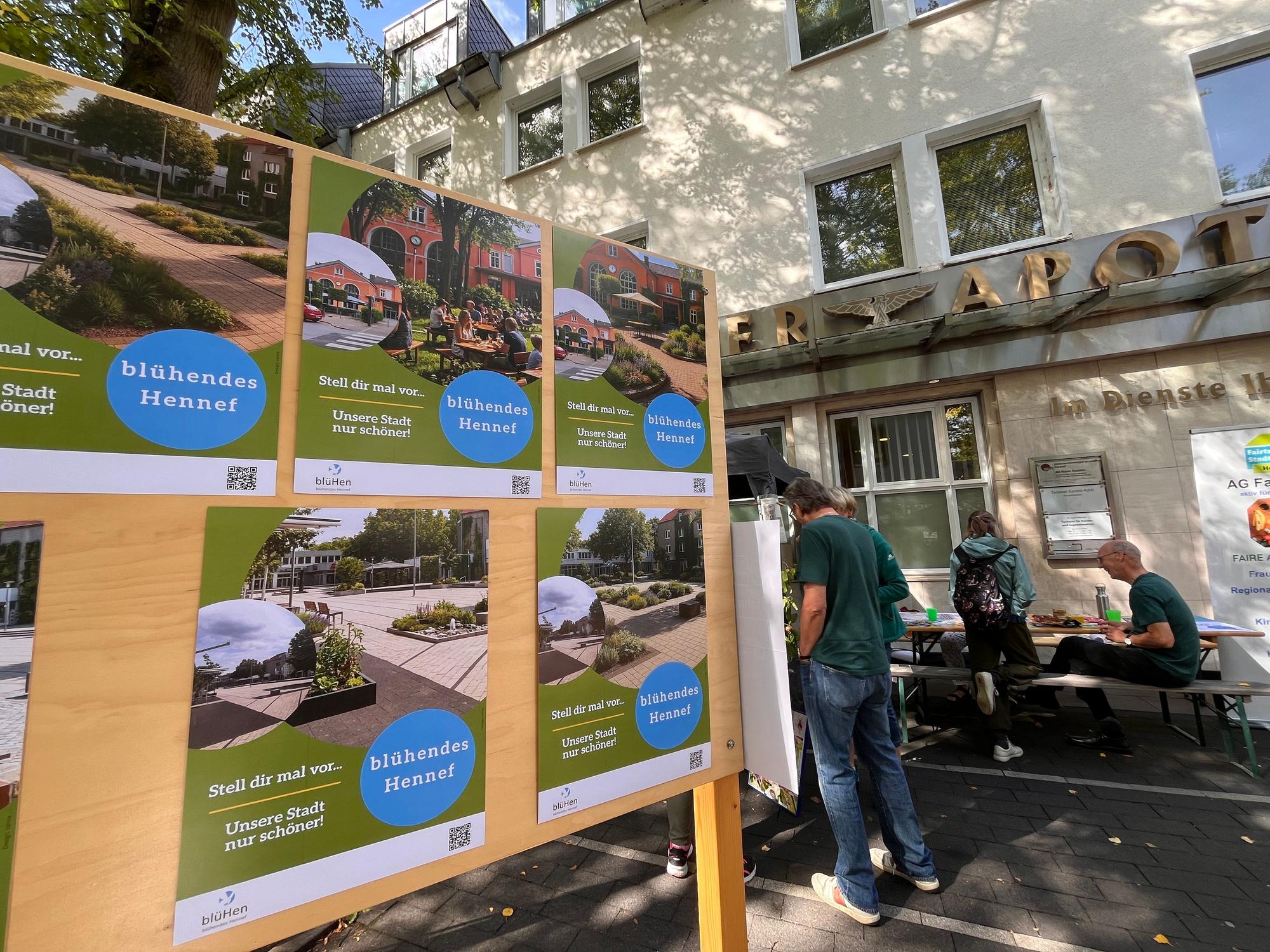 Ein Informationsstand mit kleinen Plakaten, im Hintergrund unterhalten sich Menschen.