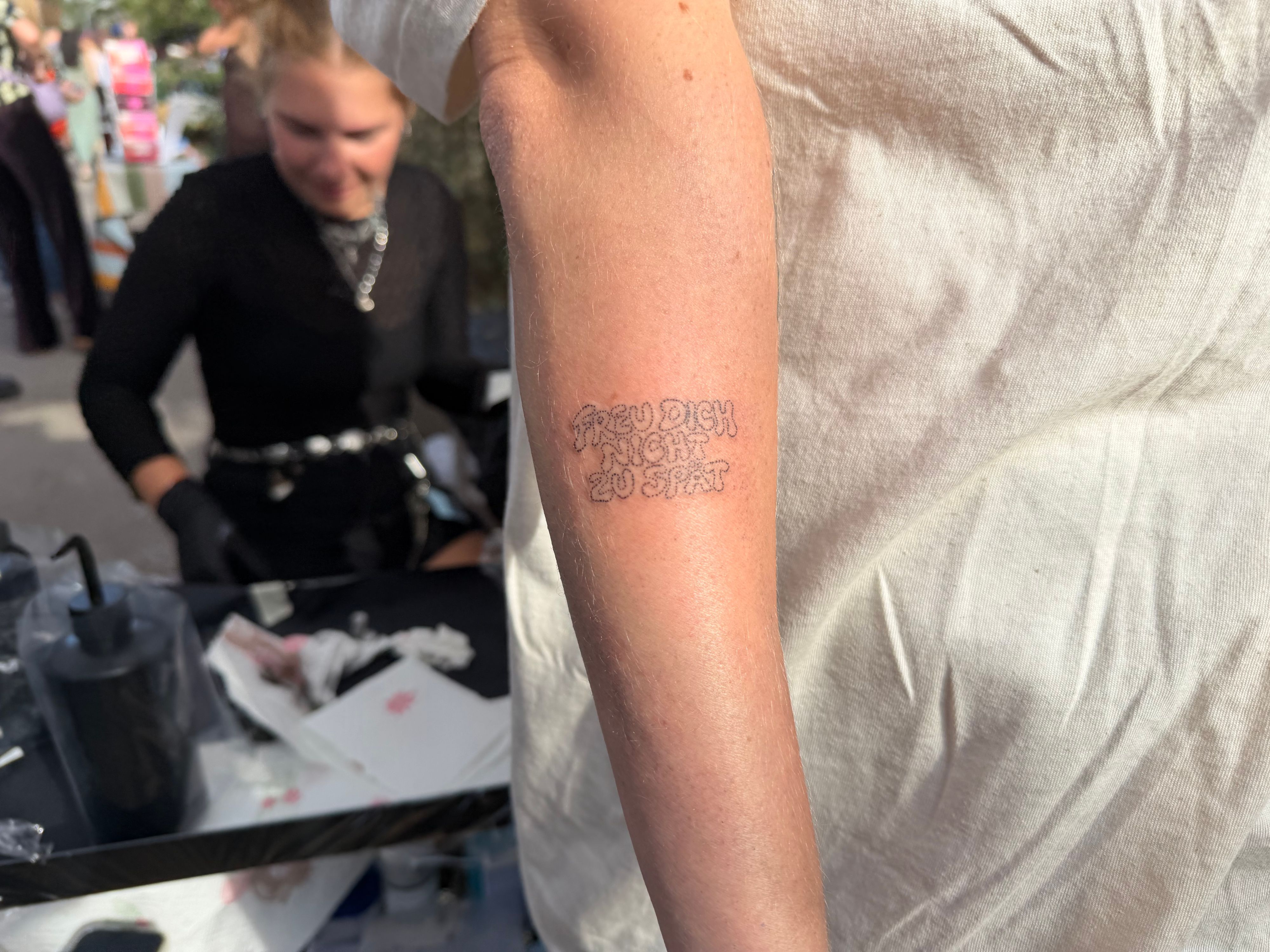 Ein Arm auf dem die Worte „Freu dich nicht zu spät“ tätowiert sind.