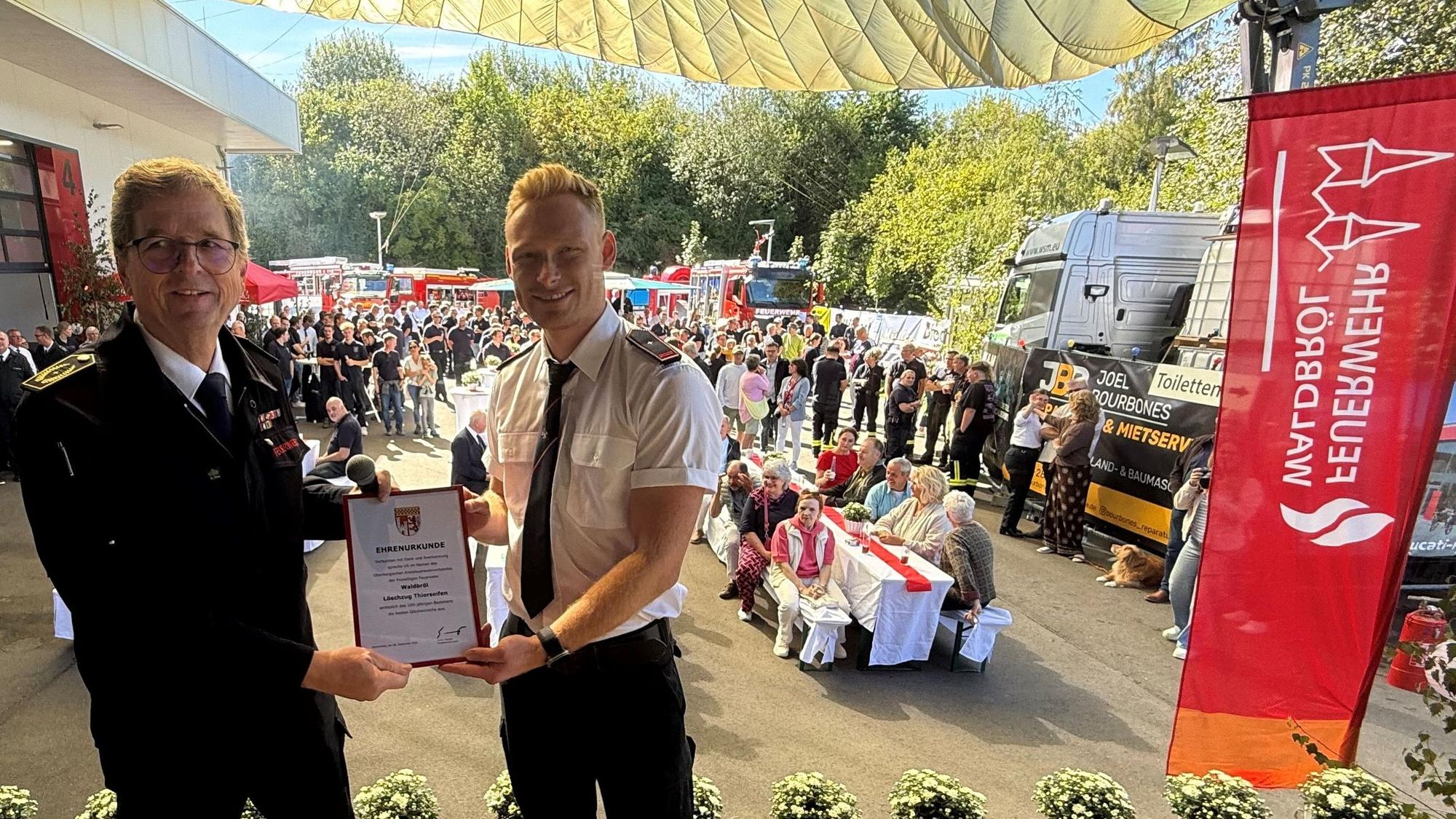 Oberbergs Vize-Kreisbrandmeister Mathias Schneider (links) übergibt die Ehrenurkunde an Philip Kramer, den Leiter des Löschzugs Thierseifen. Dieser gehört in Waldbröl zur Freiwilligen Feuerwehr.