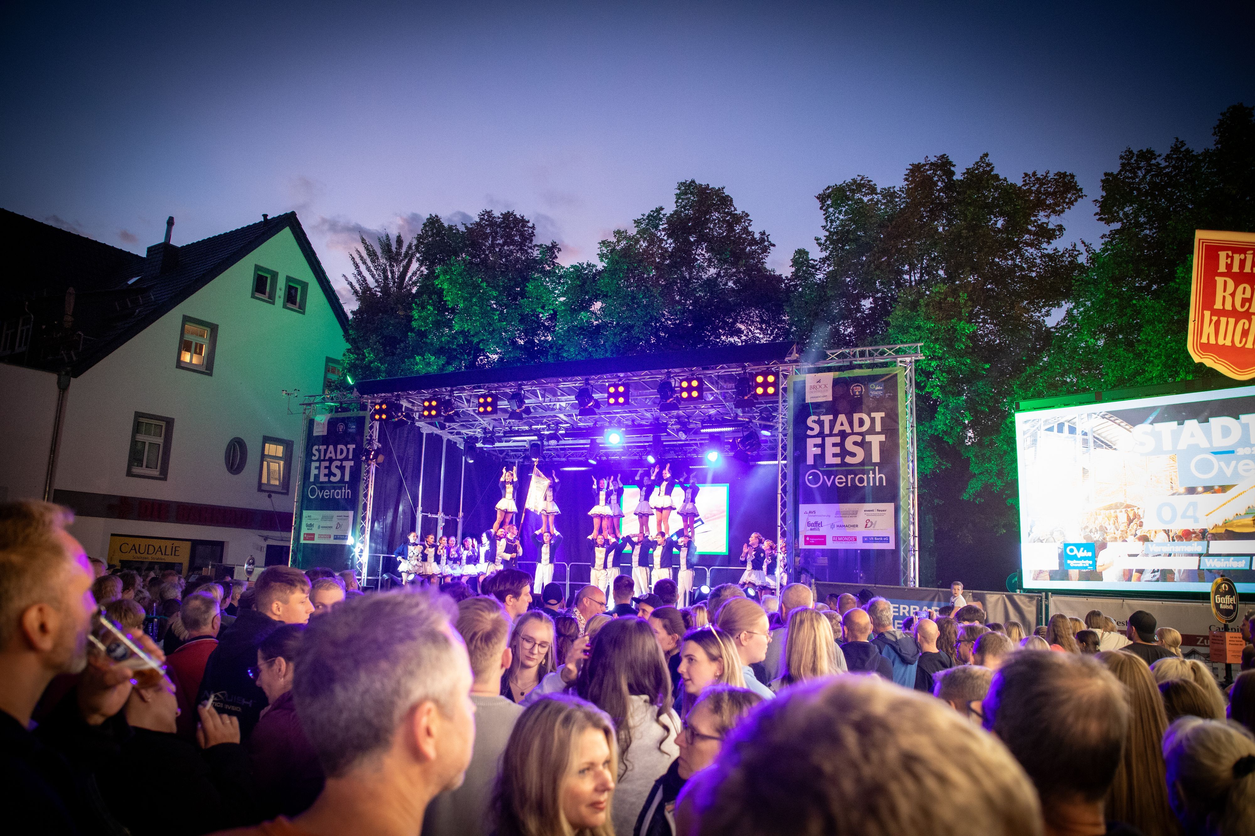 Vor der Bühne des Overather Stadtfestes sind Menschen zu sehen, die zuhören und sich unterhalten.