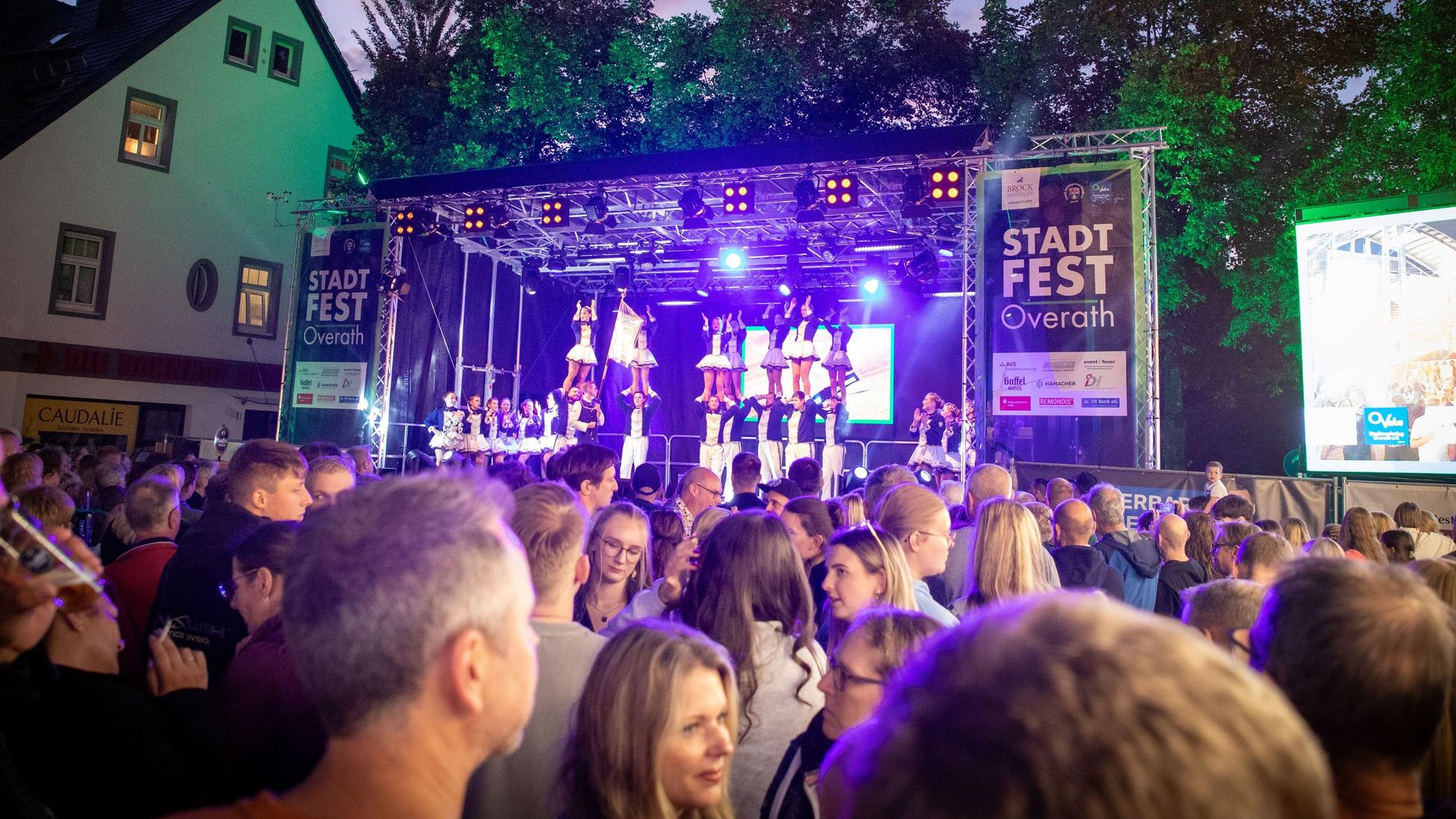 Vor der Bühne des Overather Stadtfestes sind Menschen zu sehen, die zuhören und sich unterhalten.