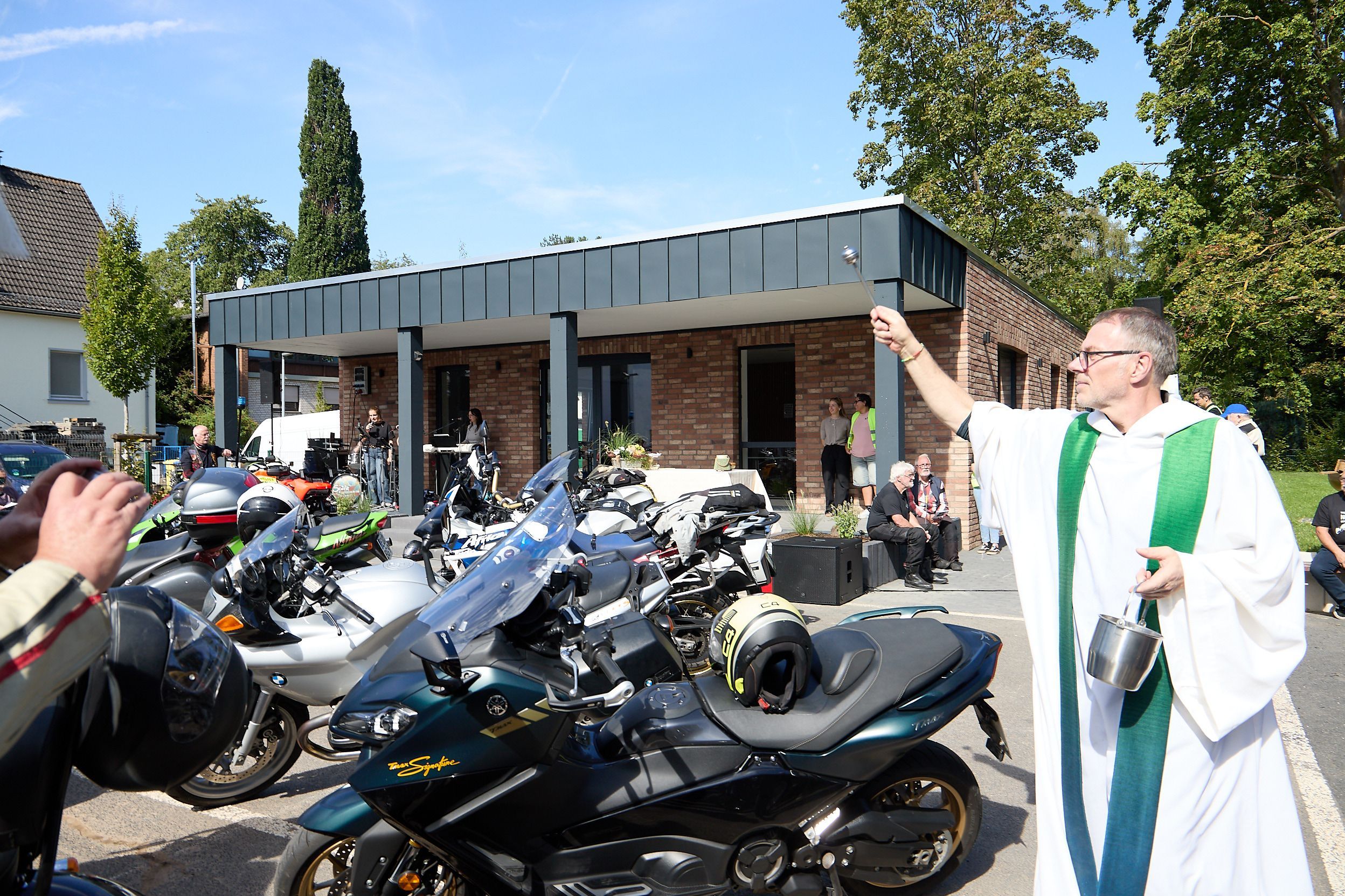 Pfarrer Hardy Hawinkels trägt ein Priestergewand und segnet Motorräder.