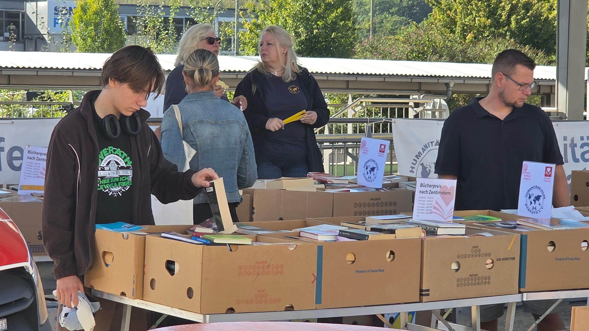 Menschen durchstöbern Kisten mit gebrauchten Büchern.