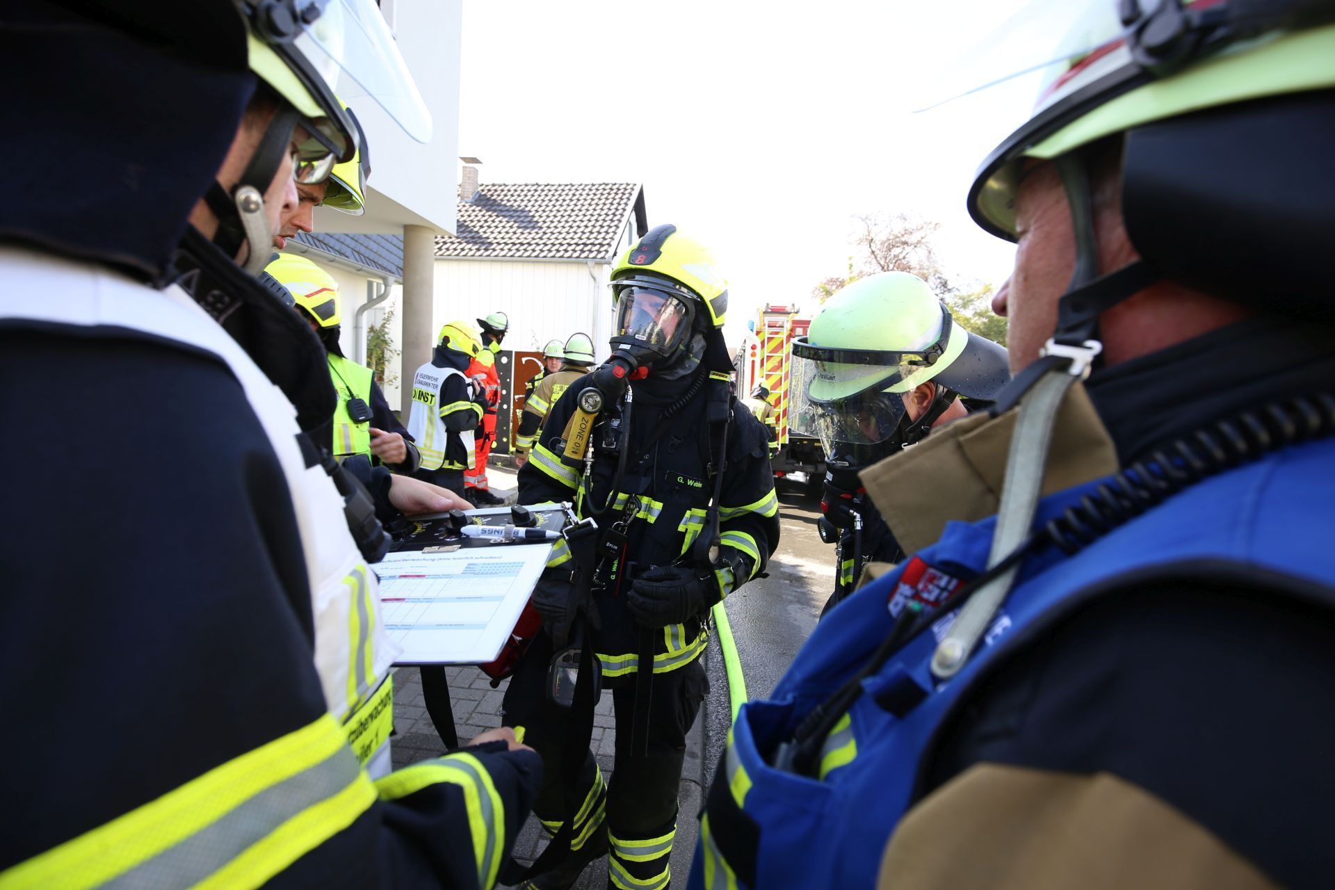 Feuerwehrleute, zum Teil mit Atemschutz, bei einem Abstimmungsgespräch mit der Einsatzleitung.