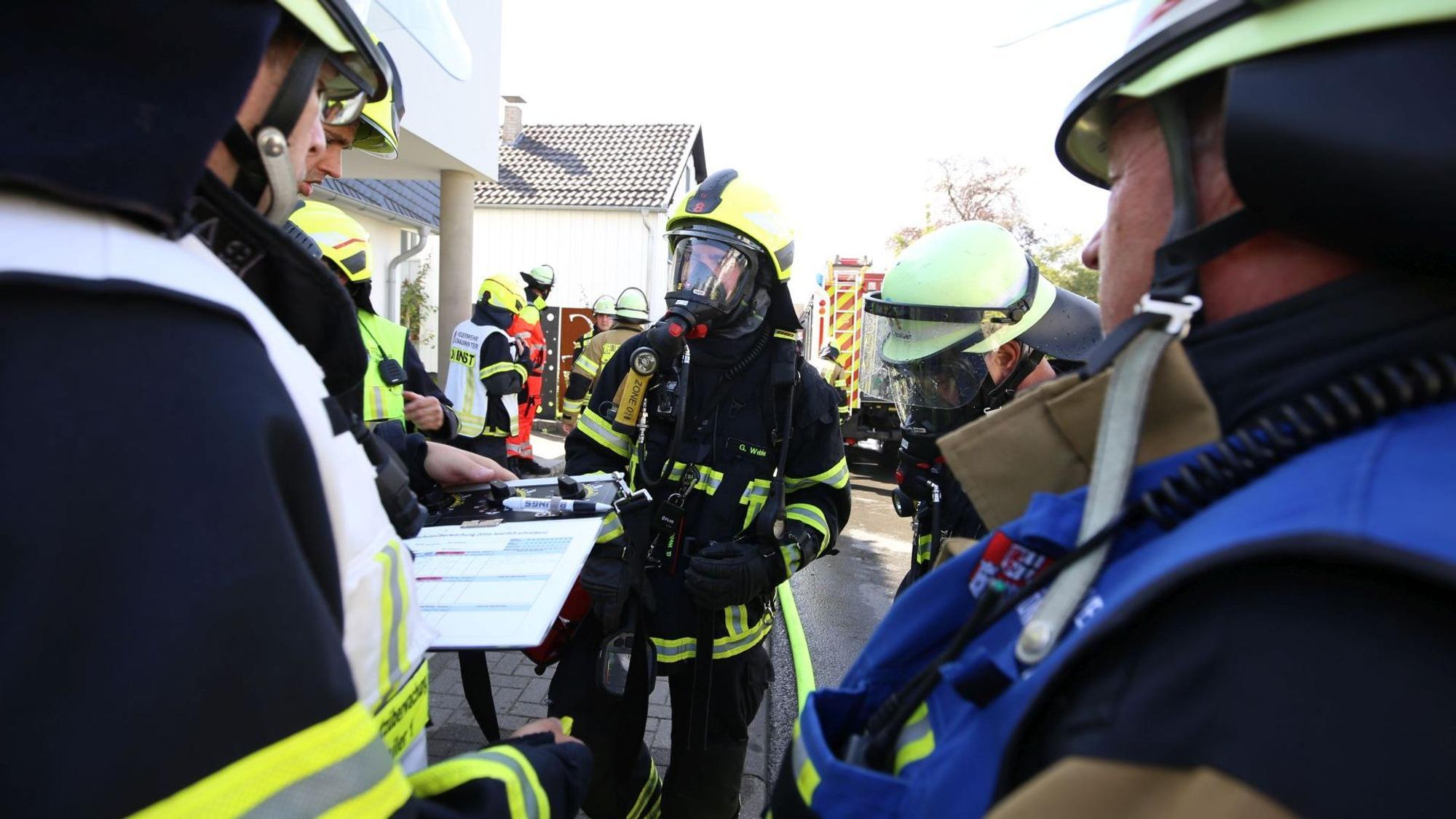 Feuerwehrleute, zum Teil mit Atemschutz, bei einem Abstimmungsgespräch mit der Einsatzleitung.