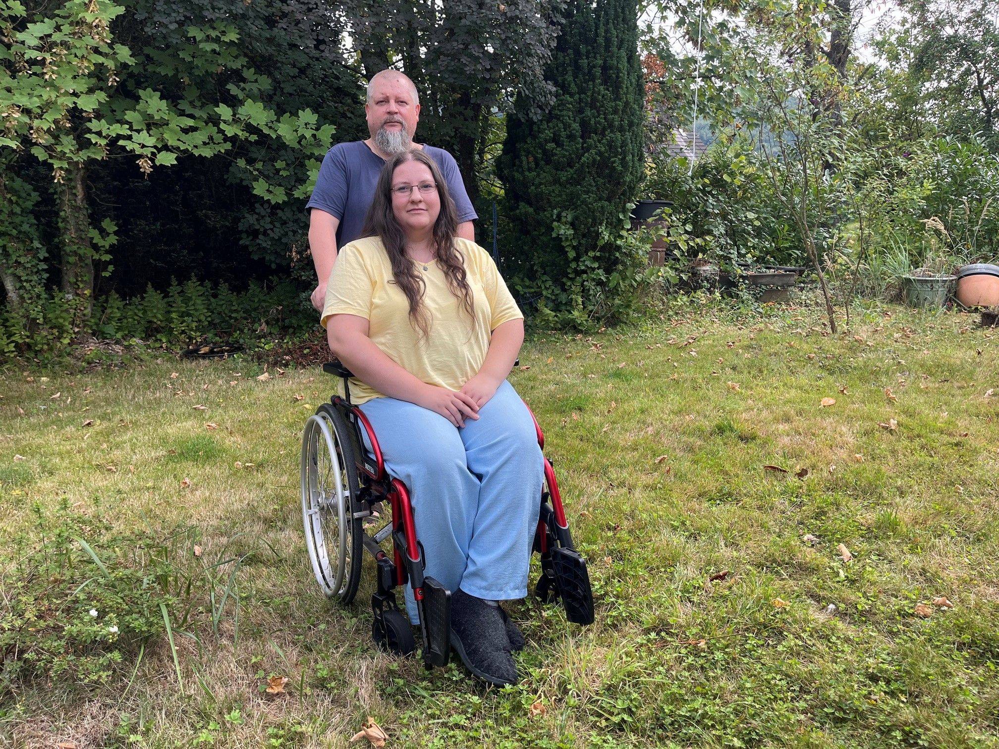 Der Vater steht hinter dem Rollstuhl, in dem Miriam sitzt.