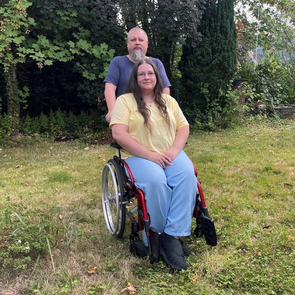 Der Vater steht hinter dem Rollstuhl, in dem Miriam sitzt.