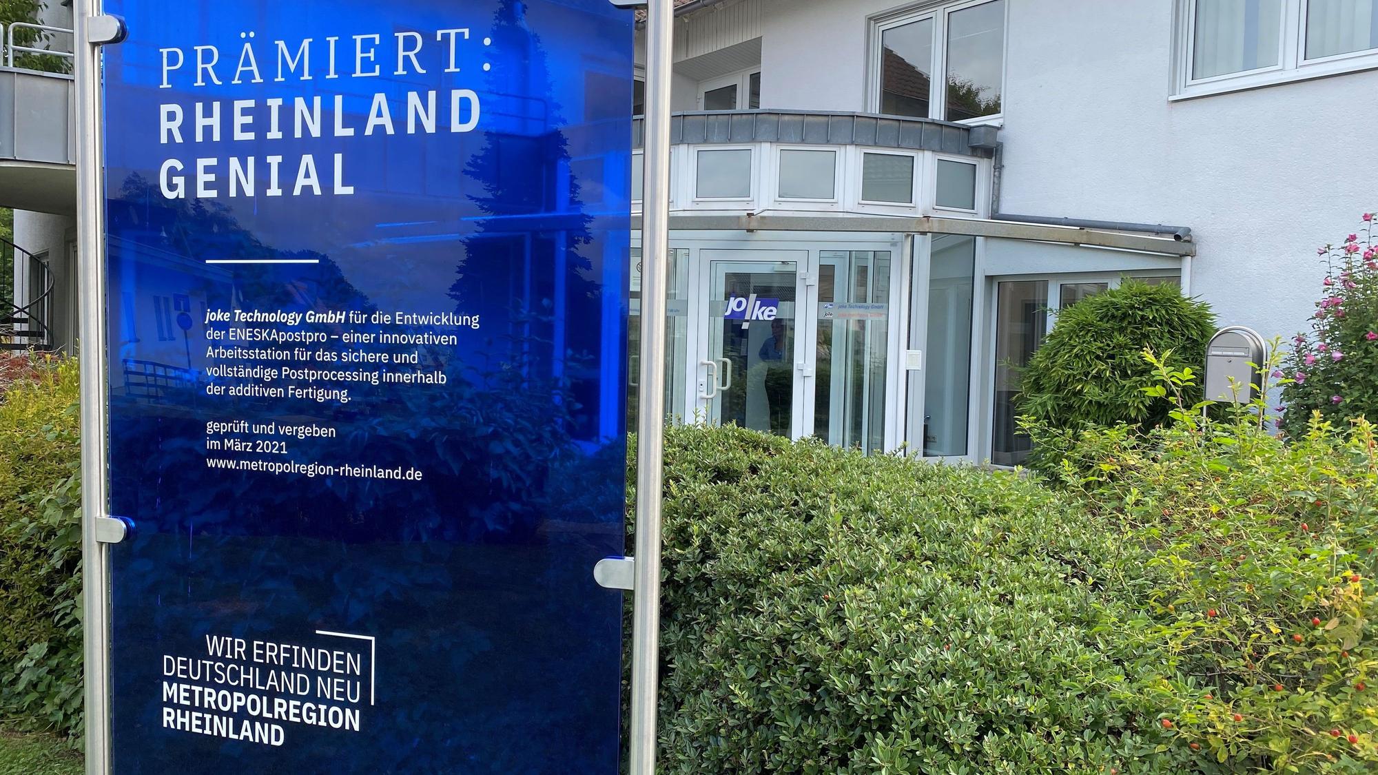 Eine Preisverleihungstafel steht vor dem Unternehmen Joke in Bergisch Gladbach-Herkenrath.