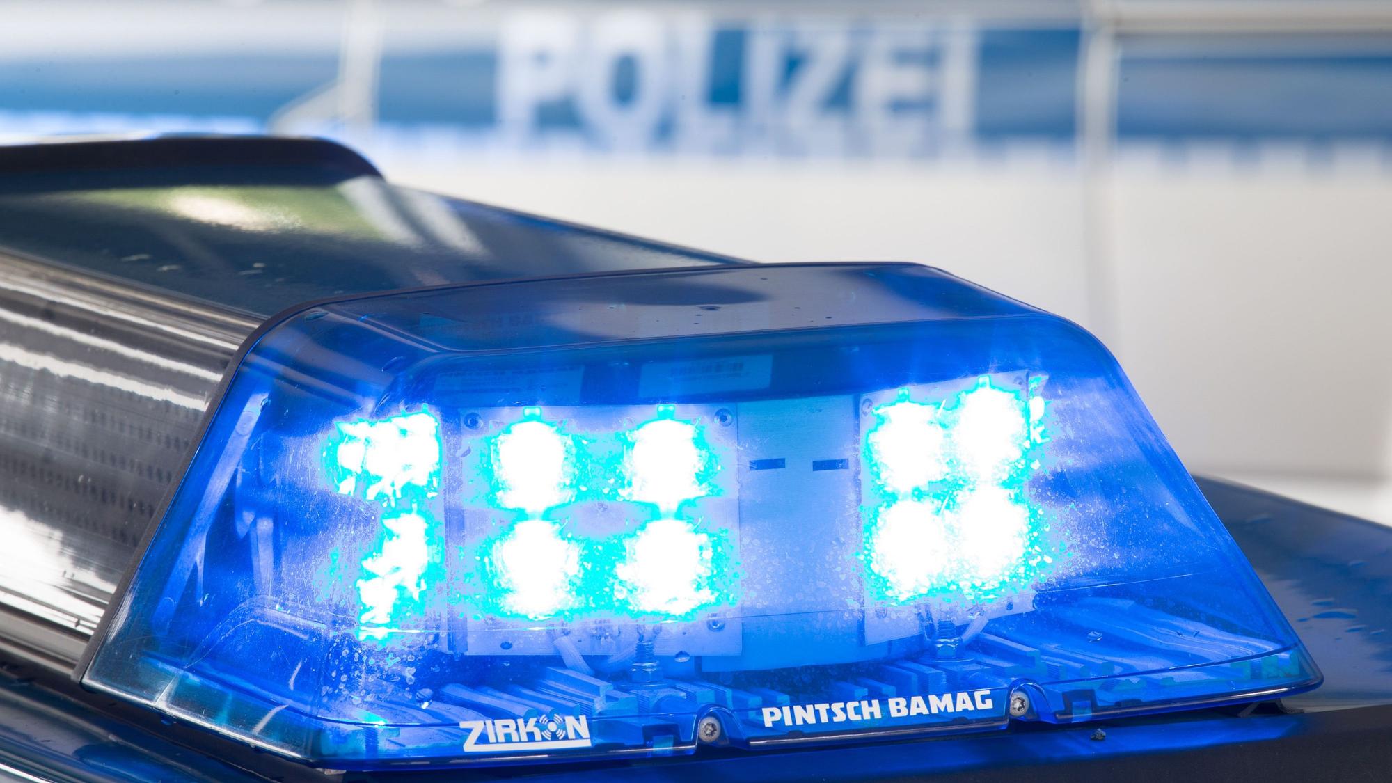 Das Foto zeigt ein Blaulicht auf dem Dach eines Einsatzfahrzeugs und ein zweites Polizeifahrzeug im Hintergrund.