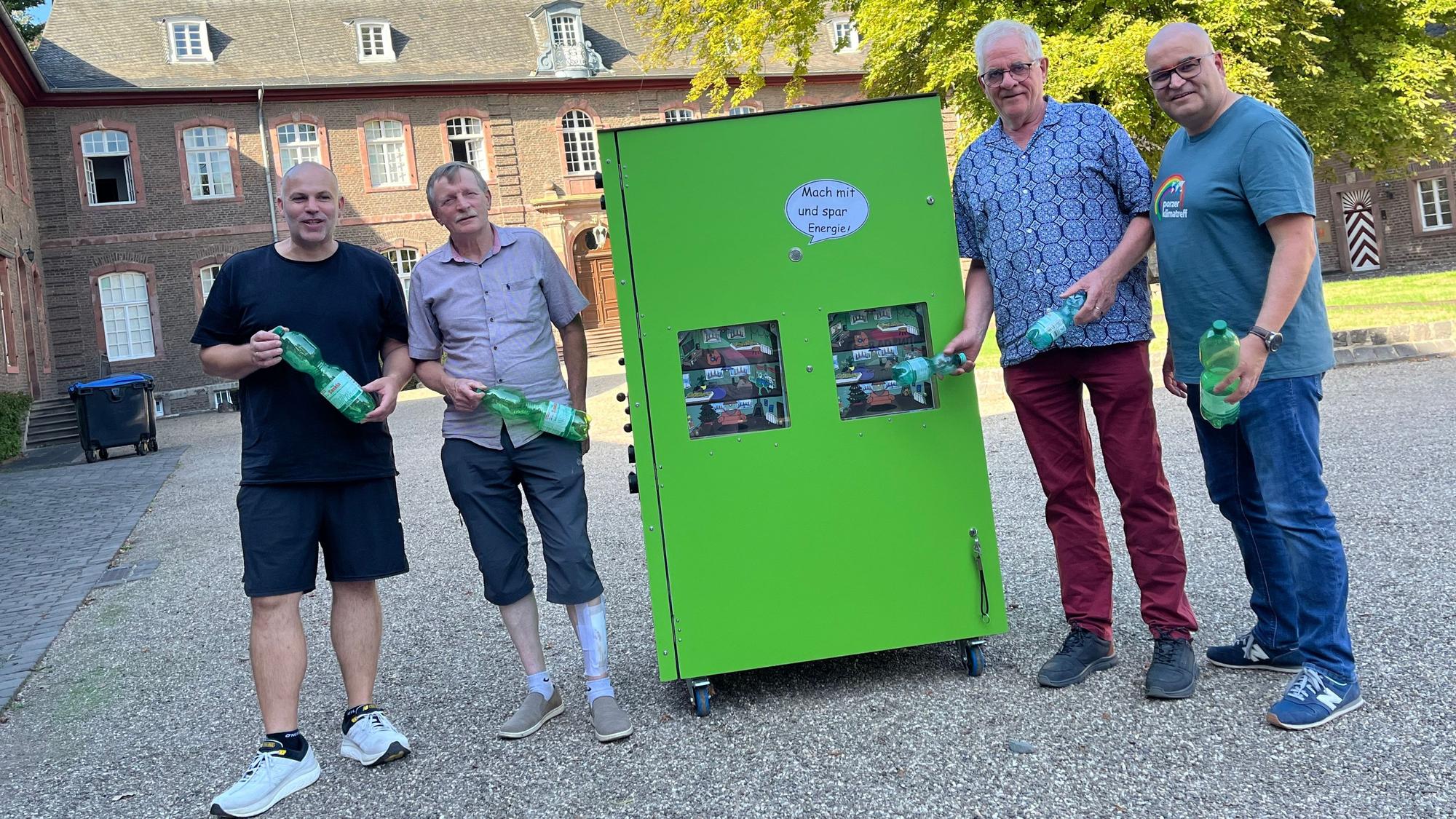 Vier Männer stehen links und rechts von einem grünen Schrank.