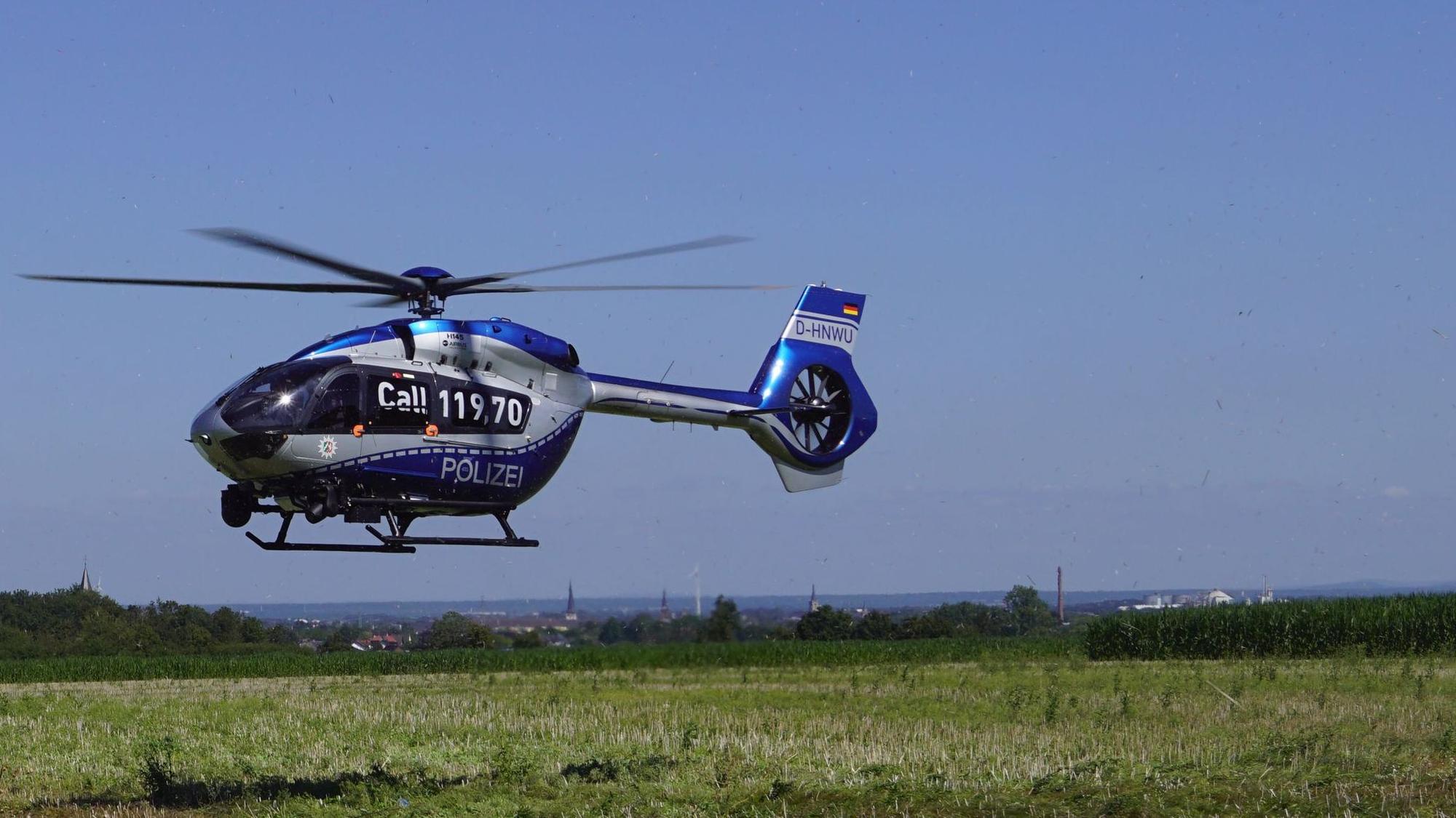 Ein Hubschrauber der Polizei landet auf einer Wiese.