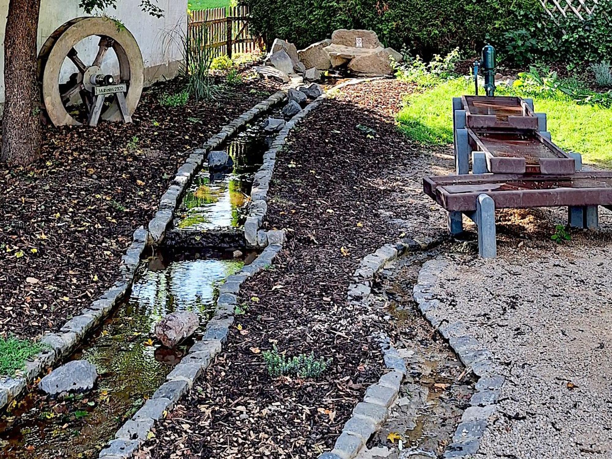 Zu sehen ist ein kleiner künstlicher Bachlauf mit einem „Matschtisch“.
