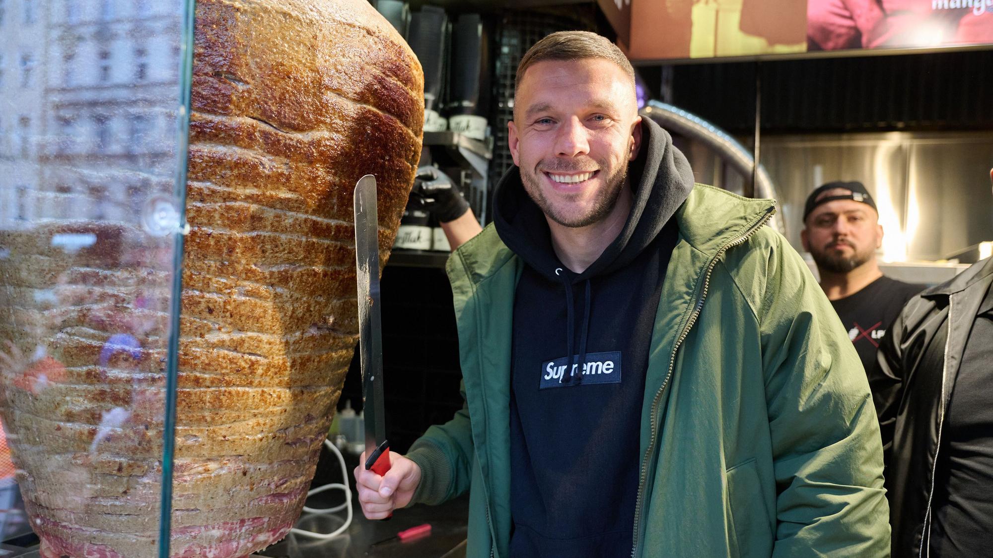 Lukas Podolski, ehemaliger Fußballprofi und Unternehmer, steht an einem Drehspieß während der Eröffnung eines „Mangal Döner“-Imbiss. (Archivbild)