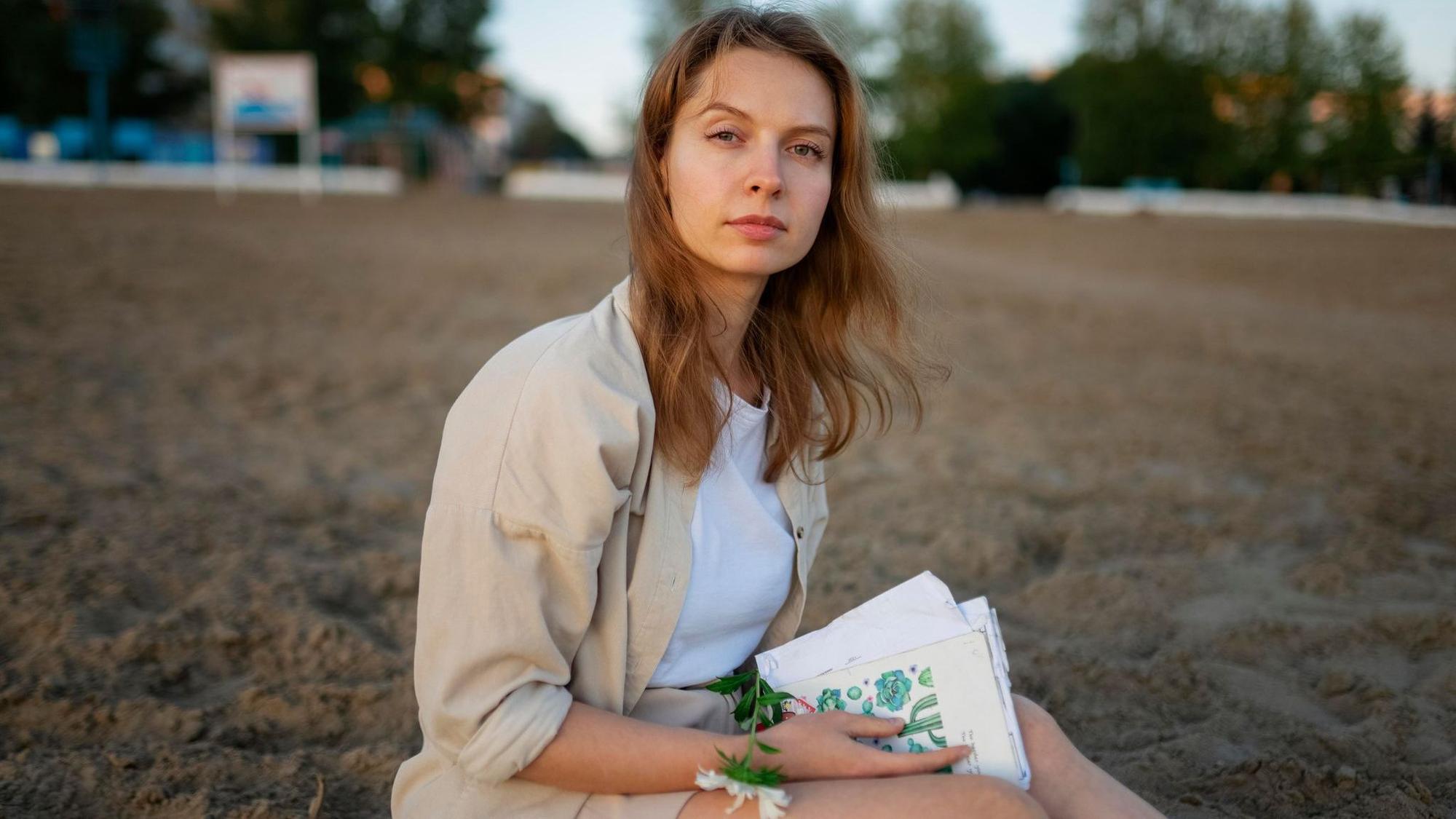 Eine Frau sitzt mit einem Buch am Strand