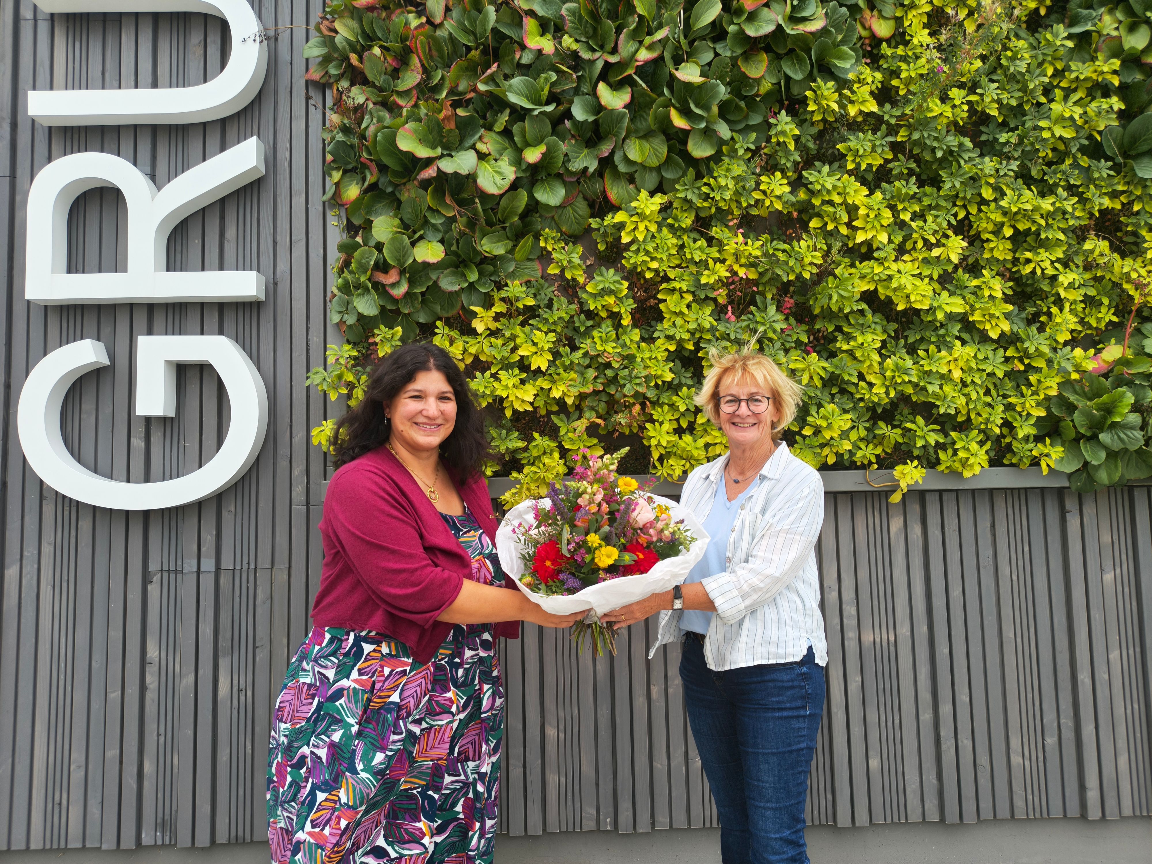 Britta Busch (r.), Geschäftsführerin des AWO-Vereins Betreute Schulen, übergibt einen Strauß Blumen an die Ogata-Leiterin Nadja Plancak (l.).