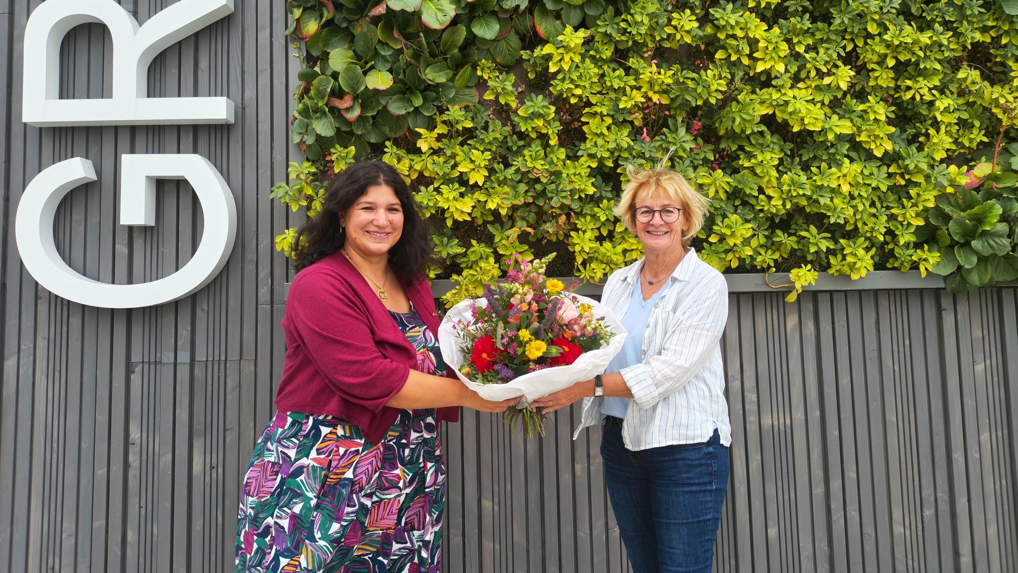 Britta Busch (r.), Geschäftsführerin des AWO-Vereins Betreute Schulen, übergibt einen Strauß Blumen an die Ogata-Leiterin Nadja Plancak (l.).