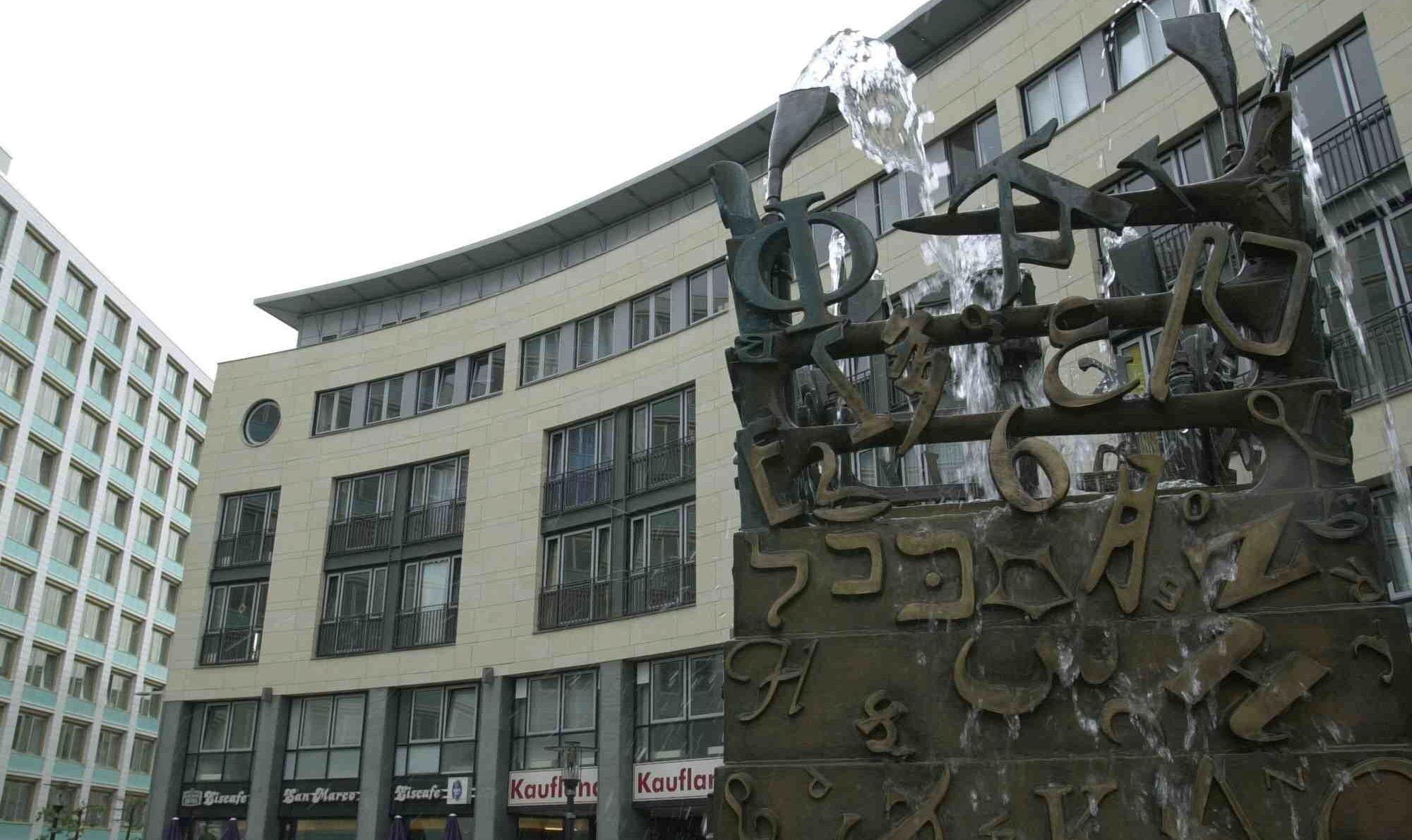 Ein Brunnen steht vor einem großen Gebäudekomplex.