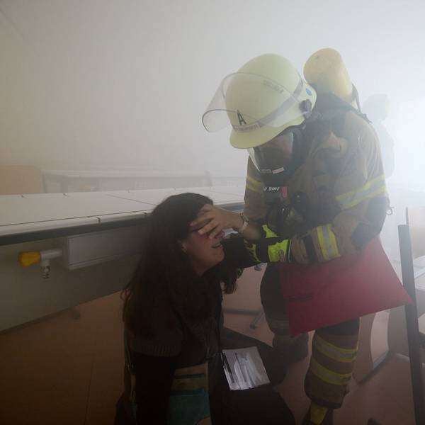 Im Nebel hat ein Feuerwehrmann eine Verletzten gefunden und bringt sie in Sicherheit.