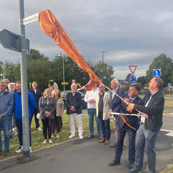 Das Foto zeigt eine Gruppe von Menschen bei der Enthüllung eines Straßenschilds.