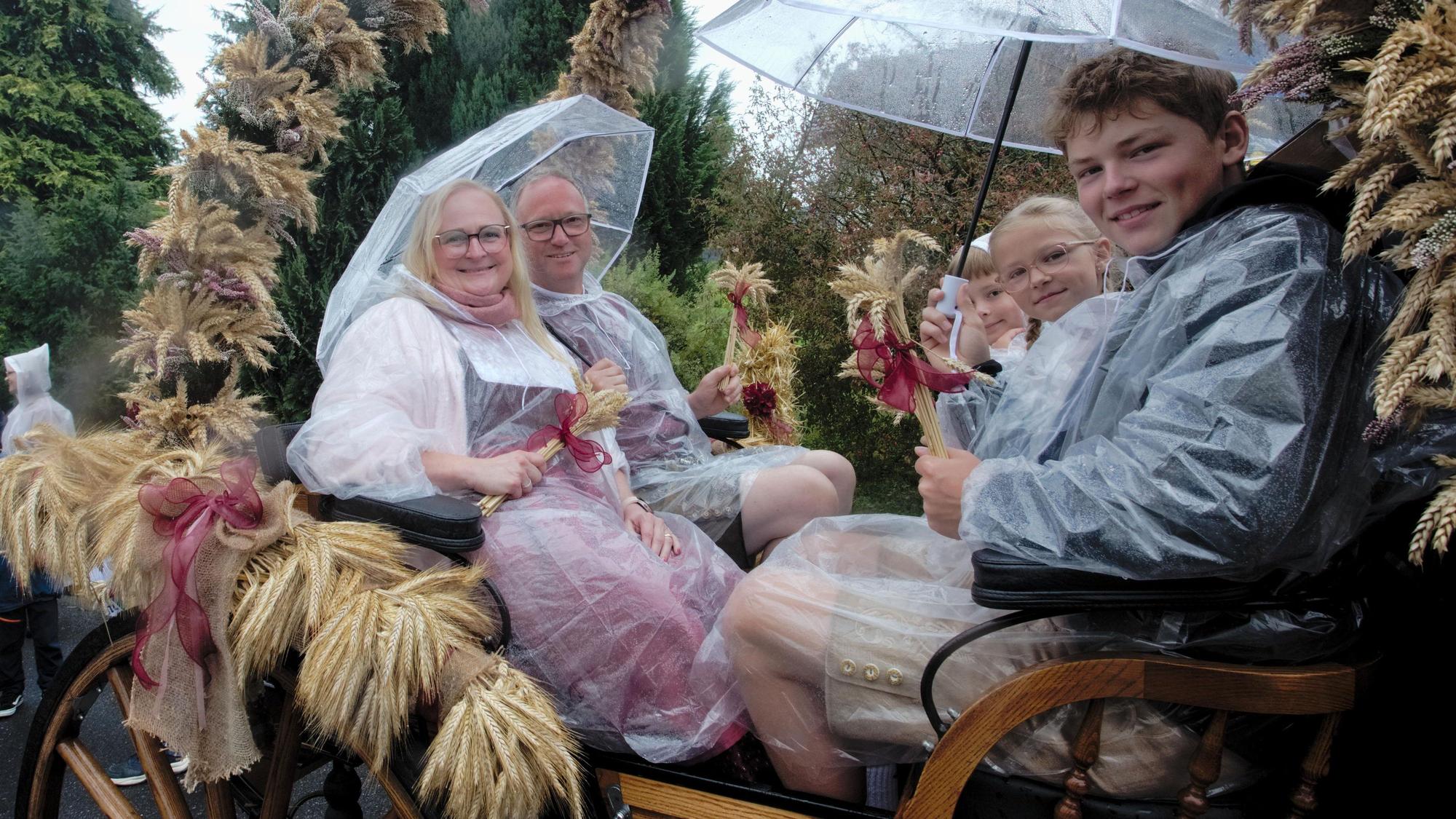Das Erntepaar Rabea und Thorsten Reuter hat sich mit Capes und Regenschirmen gegen den Regen gewappnet.