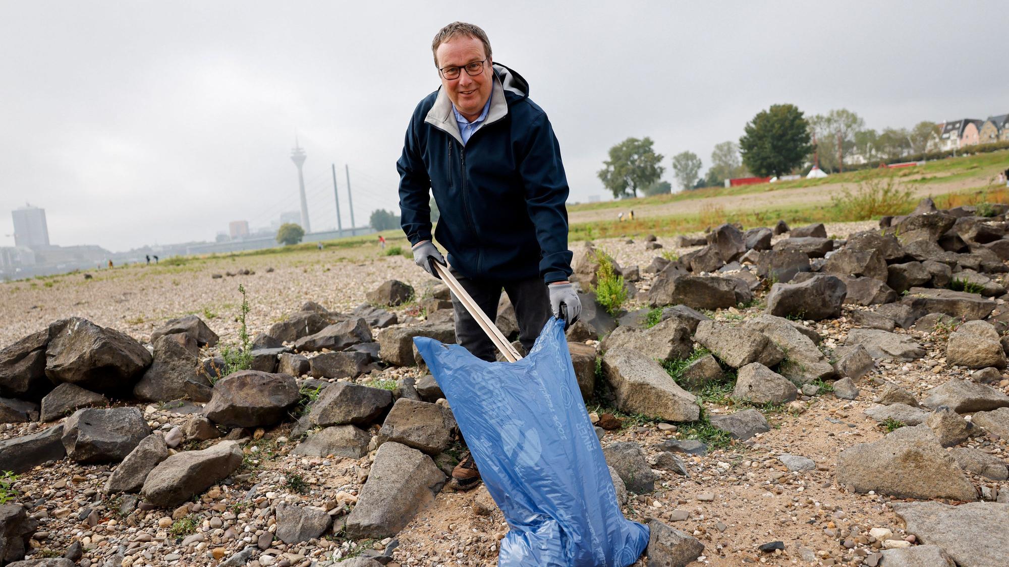 Oliver Krischer (Bündnis 90/Die Grünen), Minister für Umwelt, Naturschutz und Verkehr des Landes Nordrhein-Westfalen, sammelt auf den Düsseldorfer Rheinwiesen Müll auf.