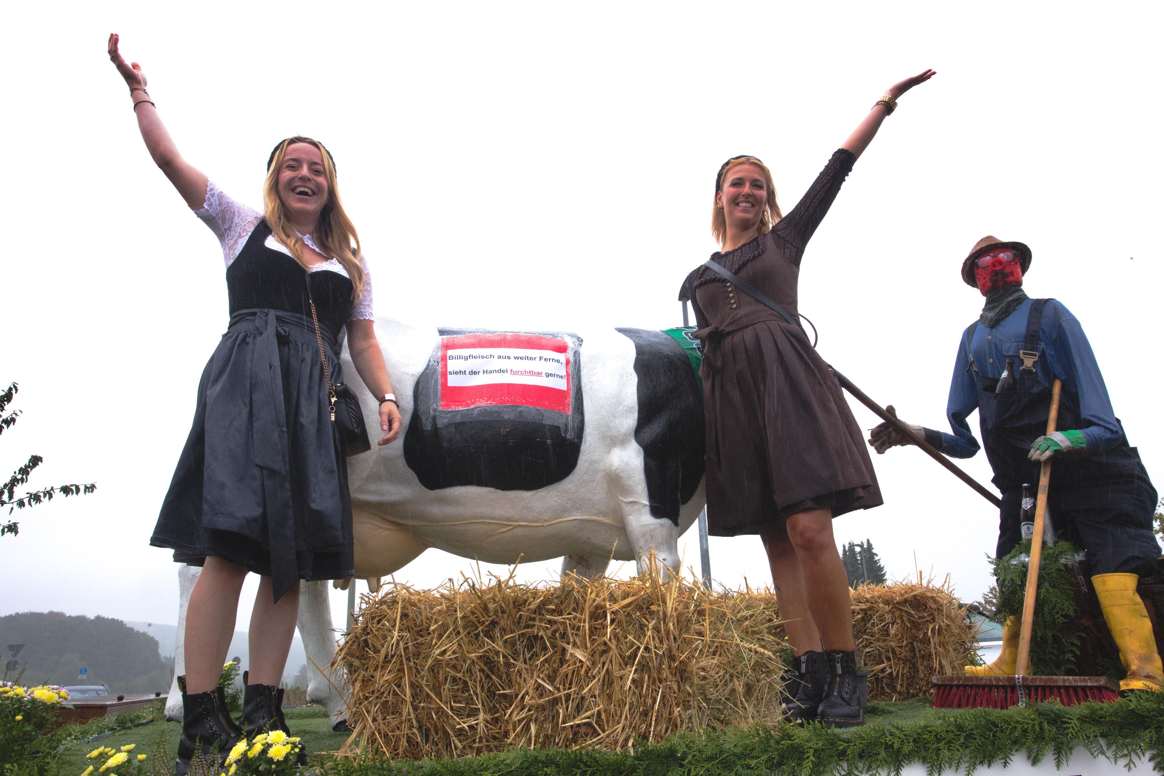 Zwei Frauen auf einem Erntewagen recken die Arme in die Höhe.