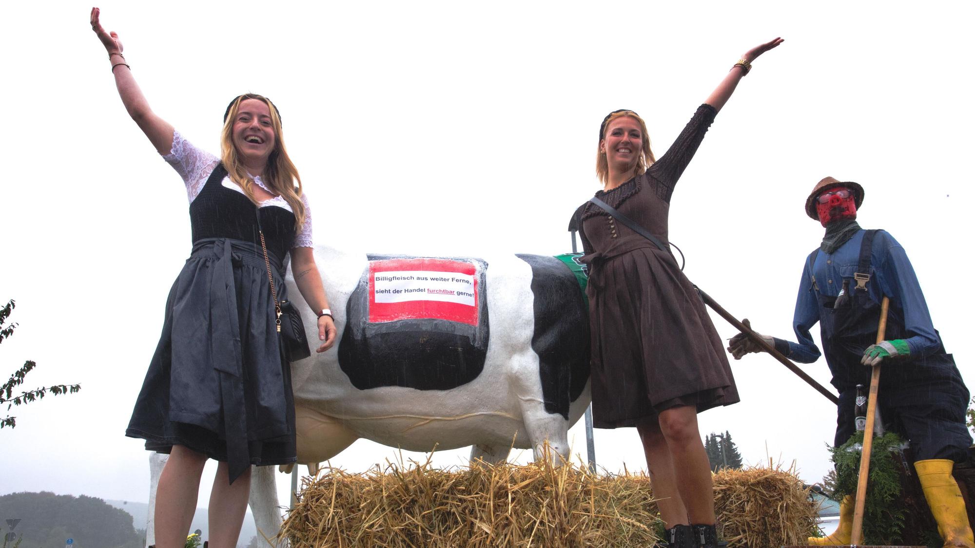Zwei Frauen auf einem Erntewagen recken die Arme in die Höhe.