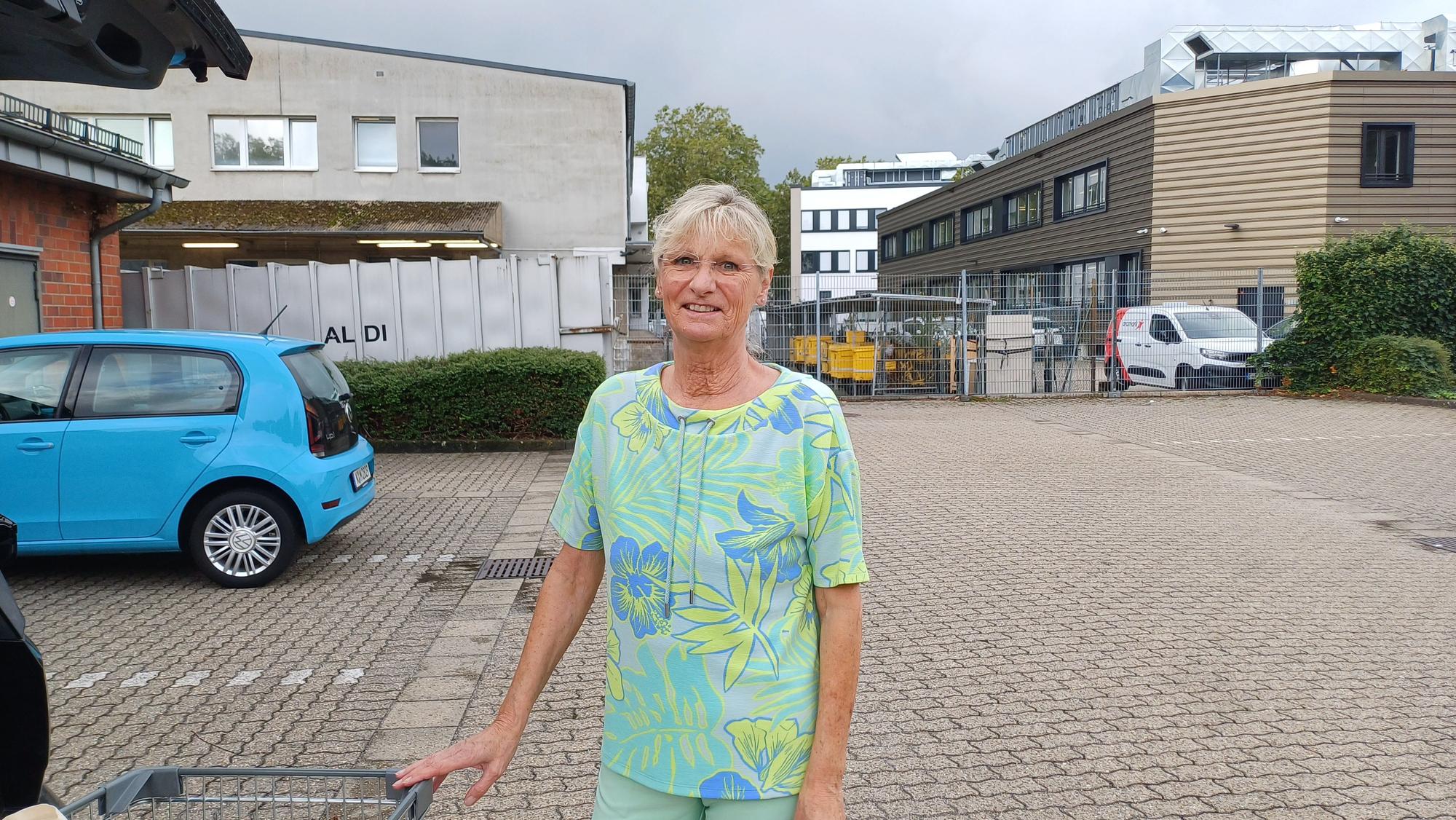 Eine Frau steht vor ihrem Auto auf dem Parkplatz