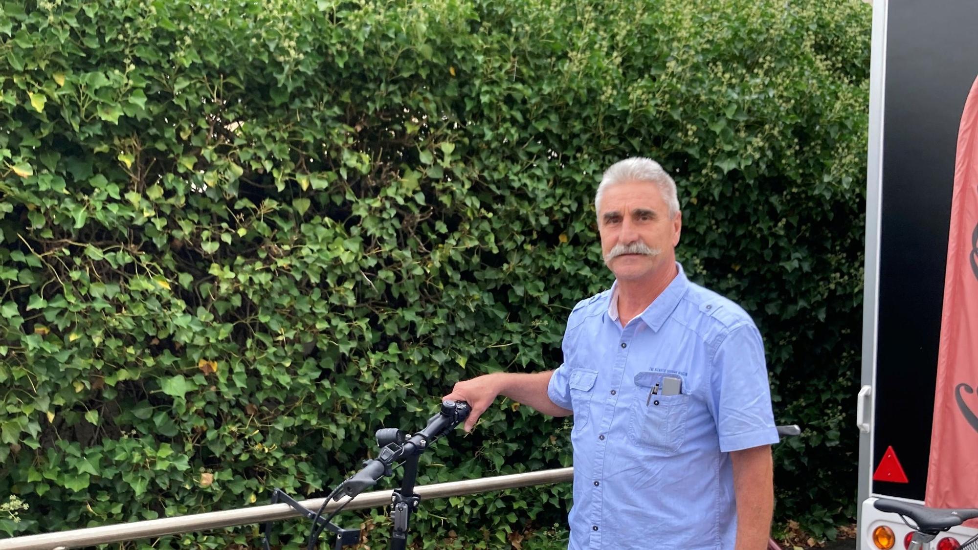 Ein Mann steht vor einer Hecke.