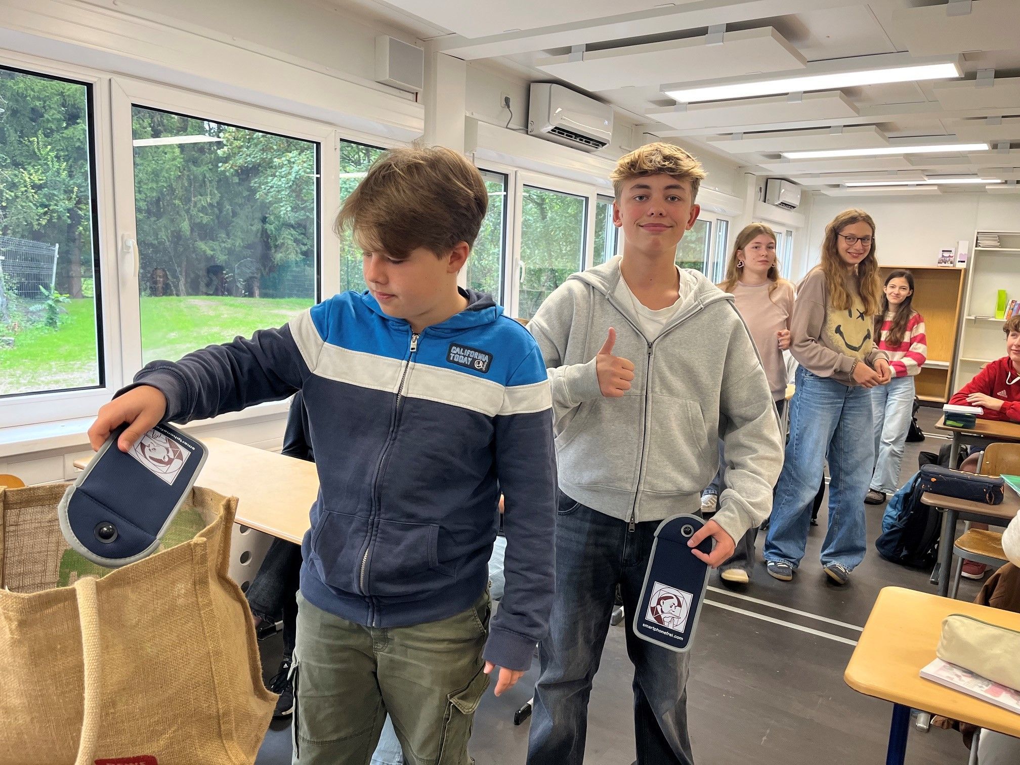 Schüler nehmen sich eine Hülle aus einer Tasche.