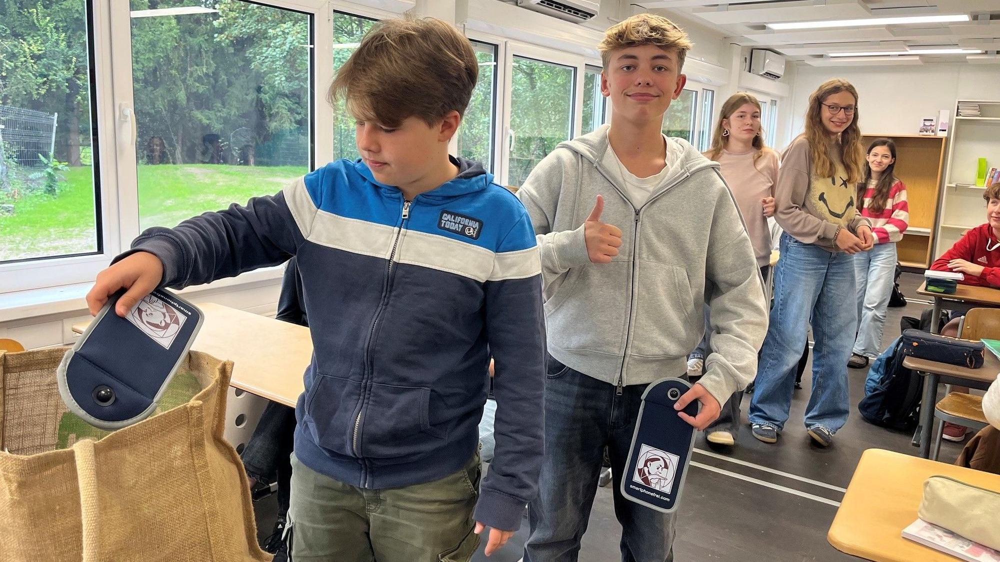 Schüler nehmen sich eine Hülle aus einer Tasche.