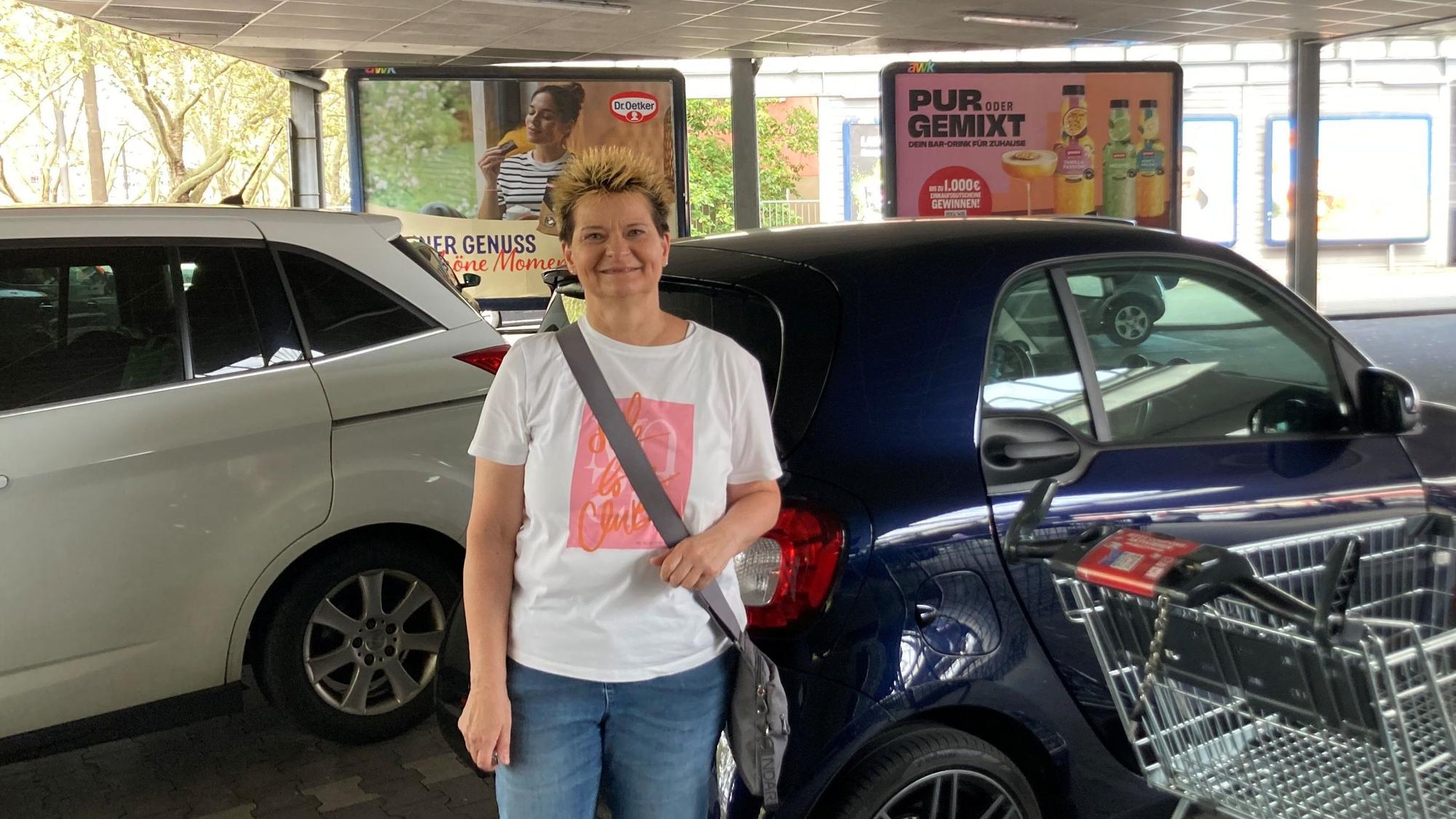 Eine Frau steht vor ihrem Auto.