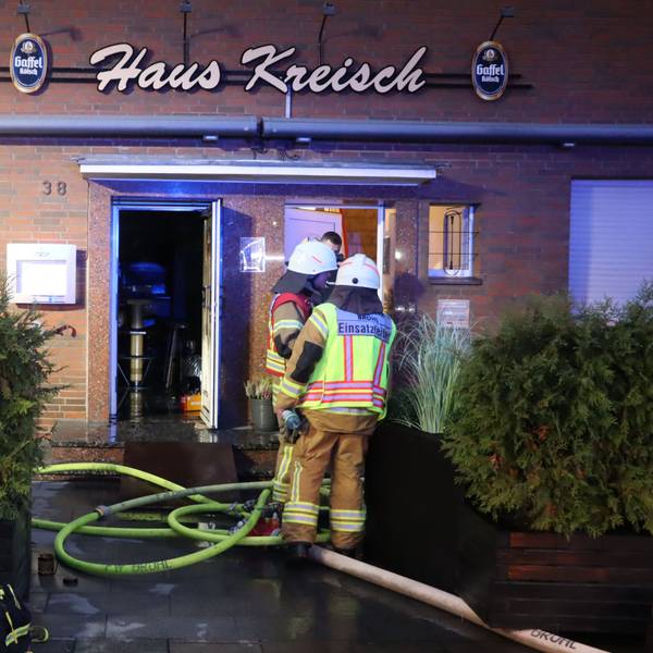 Zu sehen sind Feuerwehrleute vor dem Gebäude der Gaststätte.