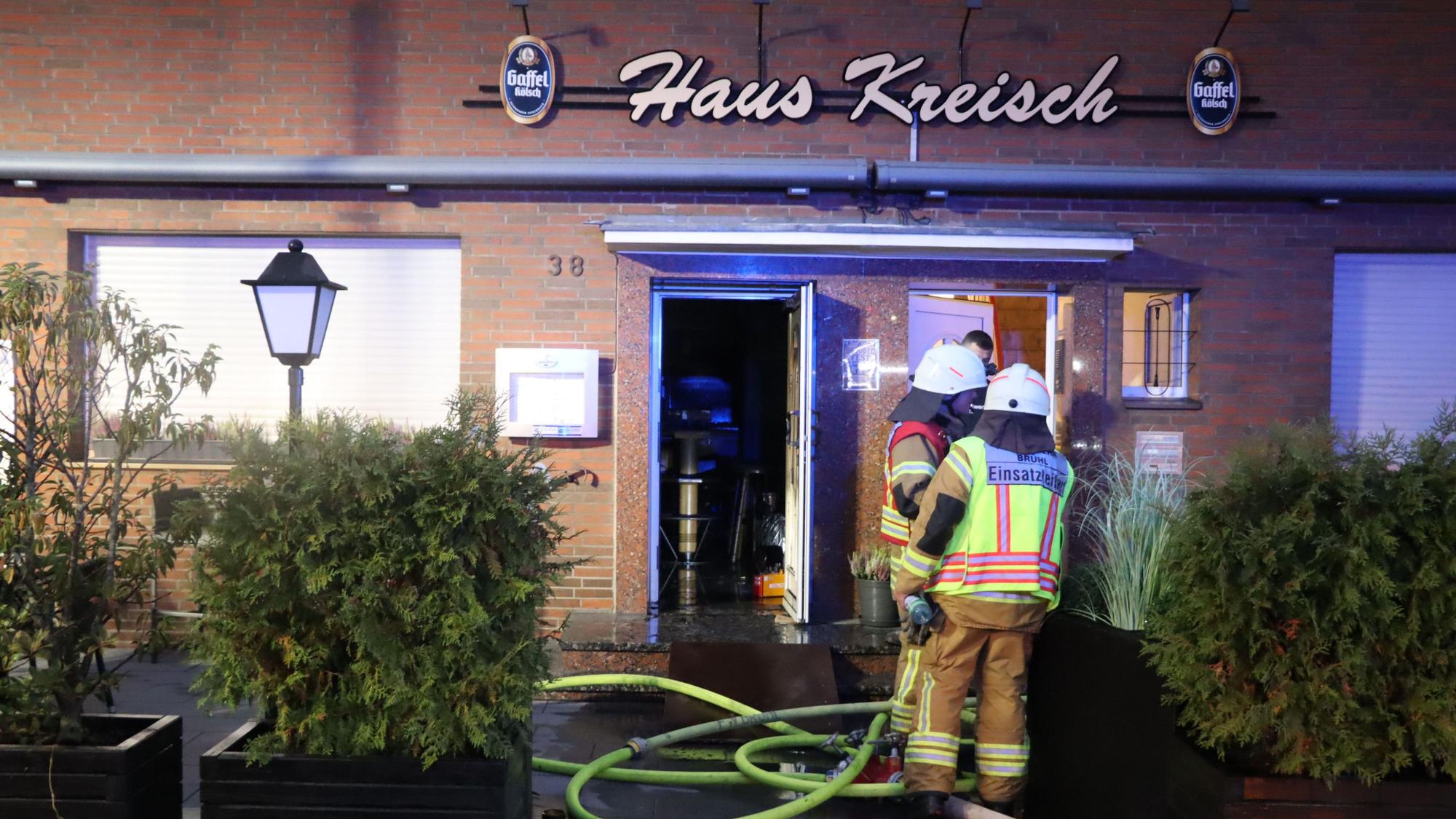 Zu sehen sind Feuerwehrleute vor dem Gebäude der Gaststätte.