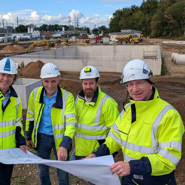 Das Foto zeigt vier Männer mit Helmen und Sicherheitswesten auf der Baustelle.
