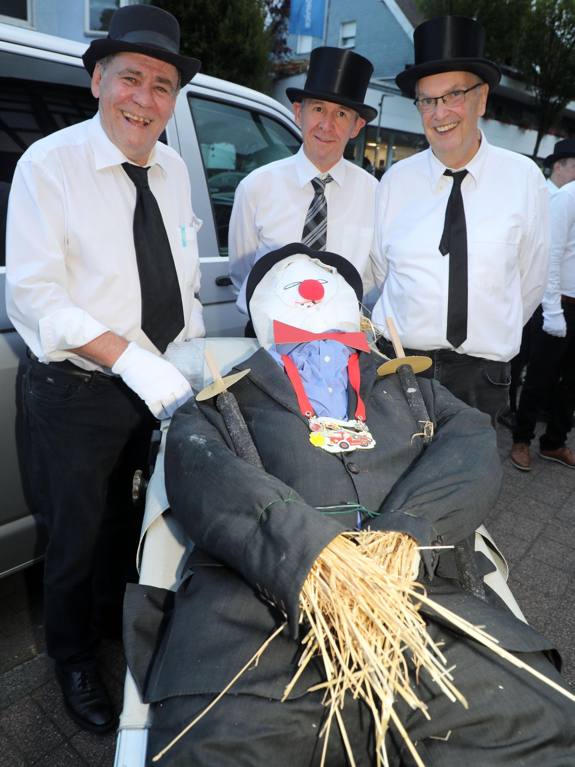 Friedel Brenner, Micky Sülz und Benedikt Promberger stehen hinter der Trage mit dem Overather Nubbel.