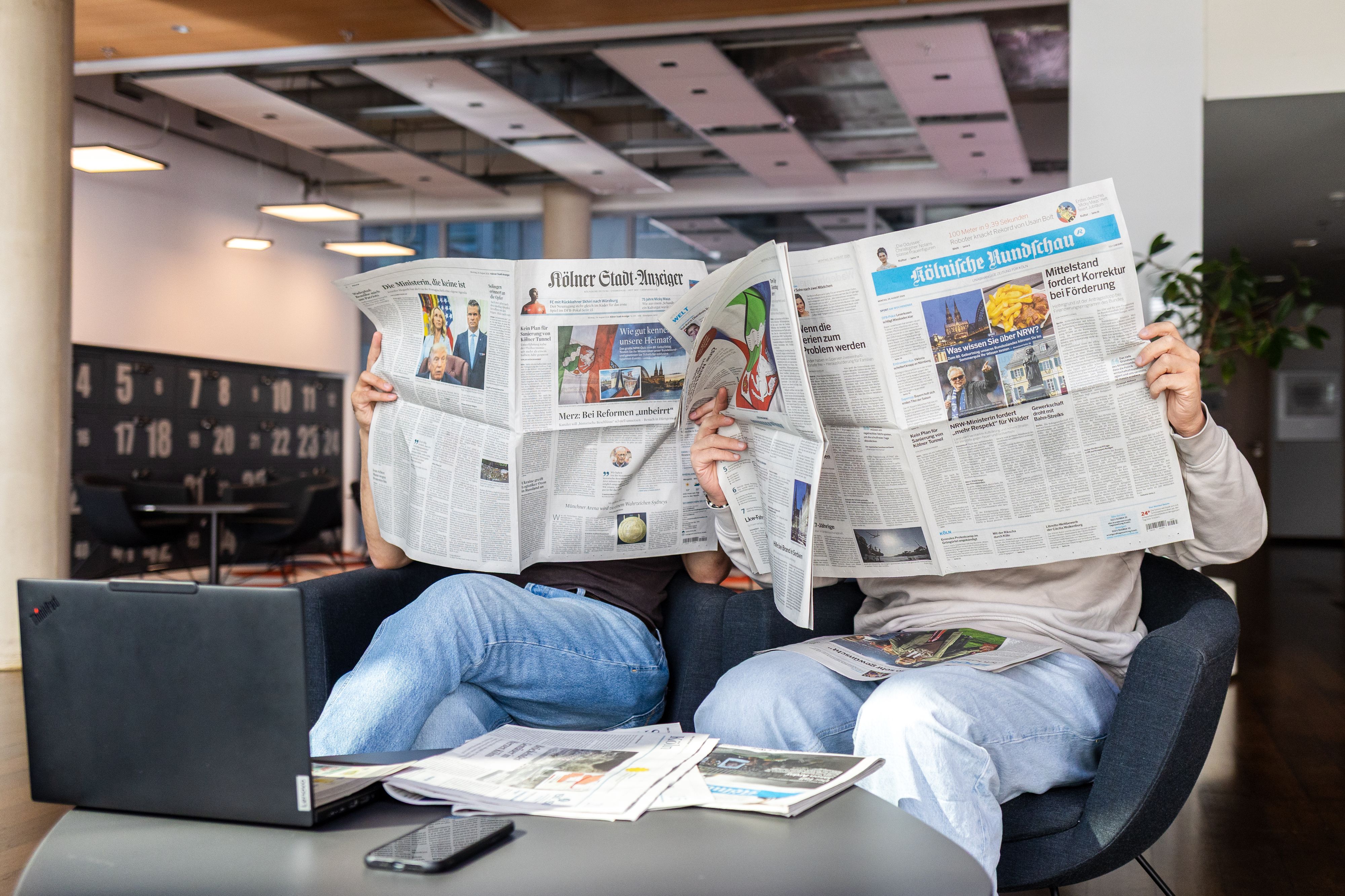 Zwei Menschen lesen Zeitung
