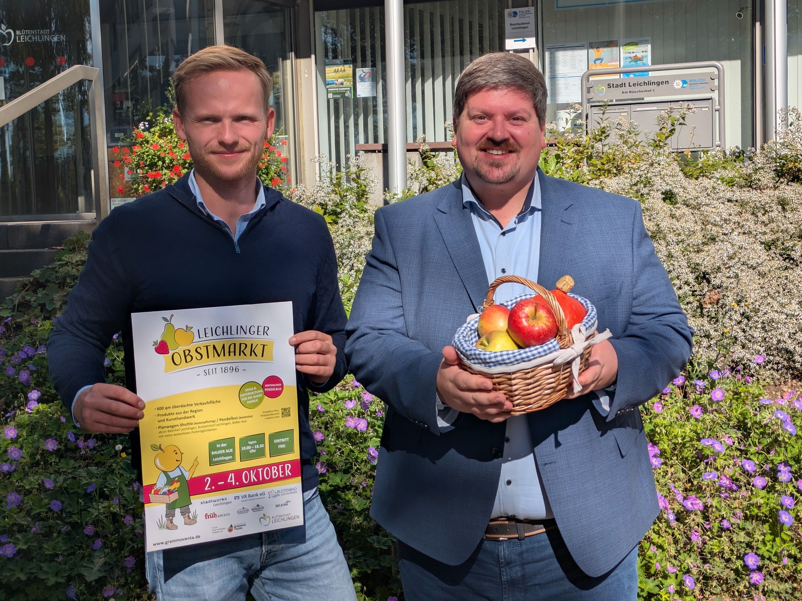 Zwei Männer halten ein Plakat und einen Obstkorb.