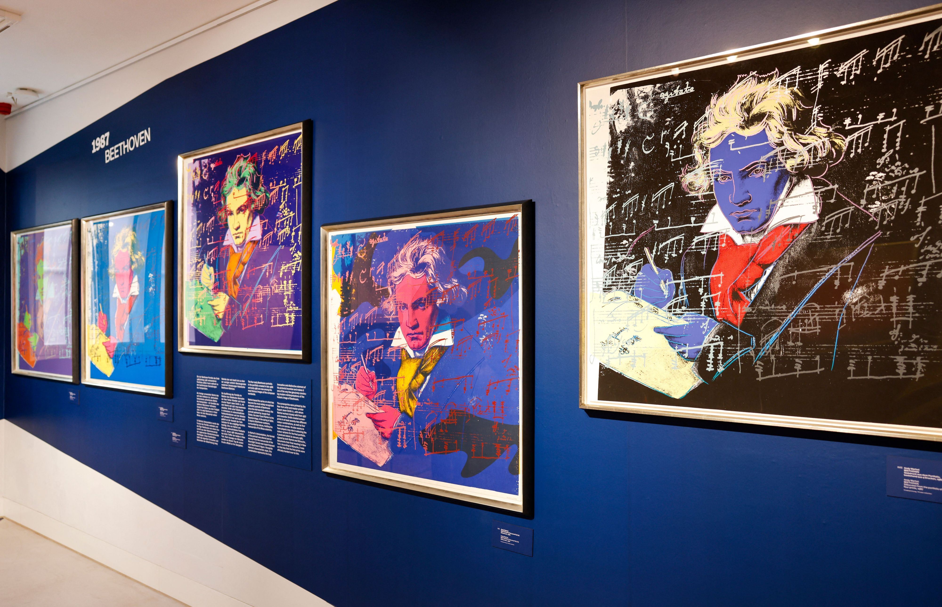 Mehrere Porträts von Beethoven hängen an einer Wand.