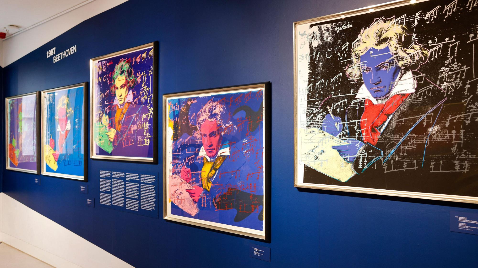 Mehrere Porträts von Beethoven hängen an einer Wand.