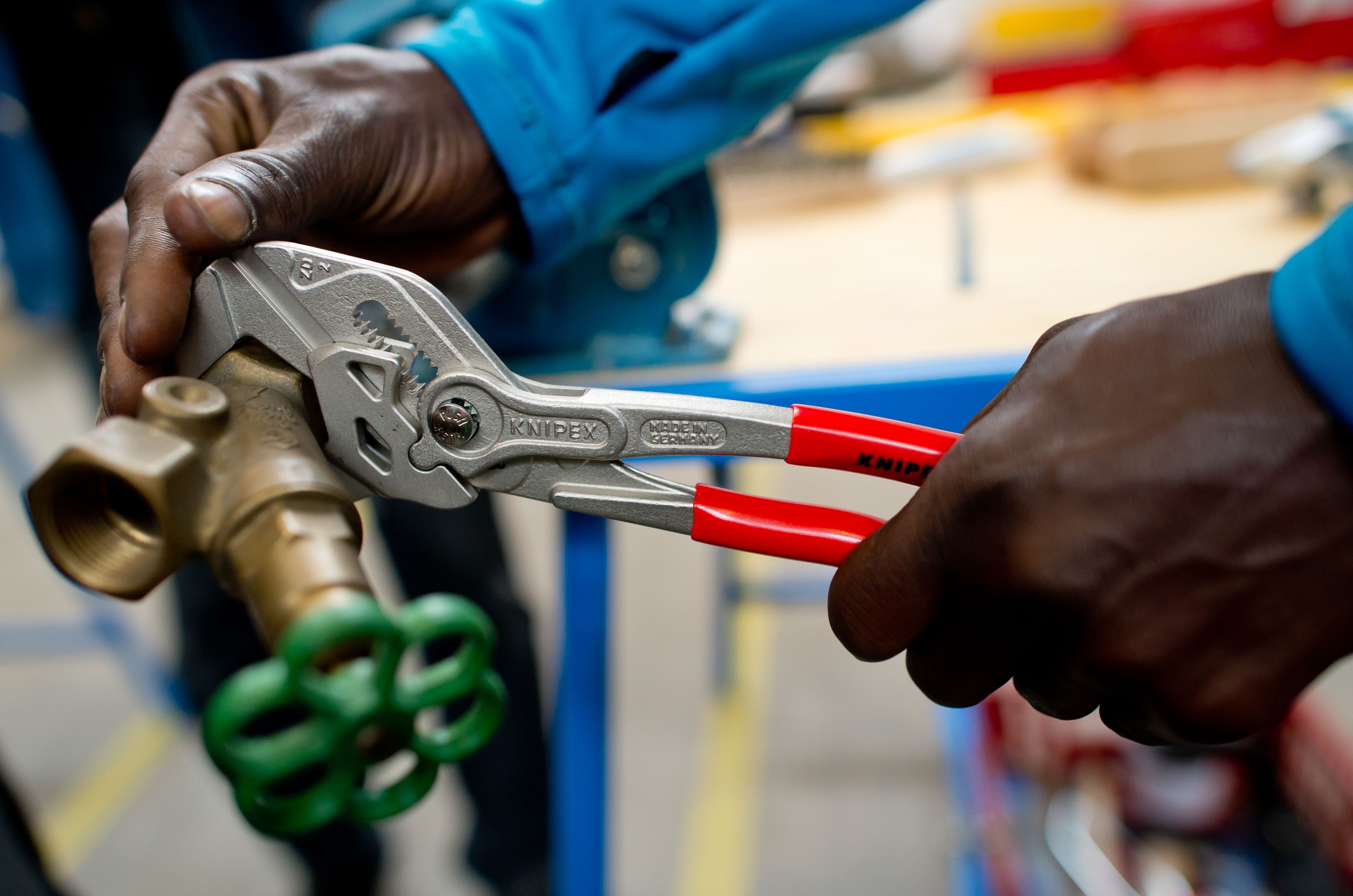 Ein Flüchtling arbeitet in einer Lernwerkstatt unter professioneller Anleitung an einem Werkstück.