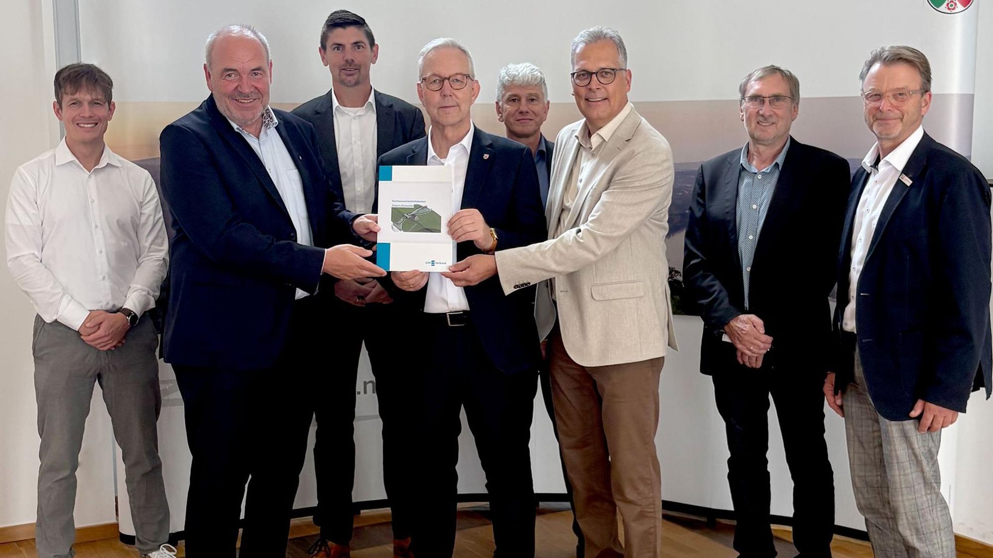 Eine Gruppe Männer hat sich versammlet, drei halten eine Mappe mit den Antragsunterlagen.