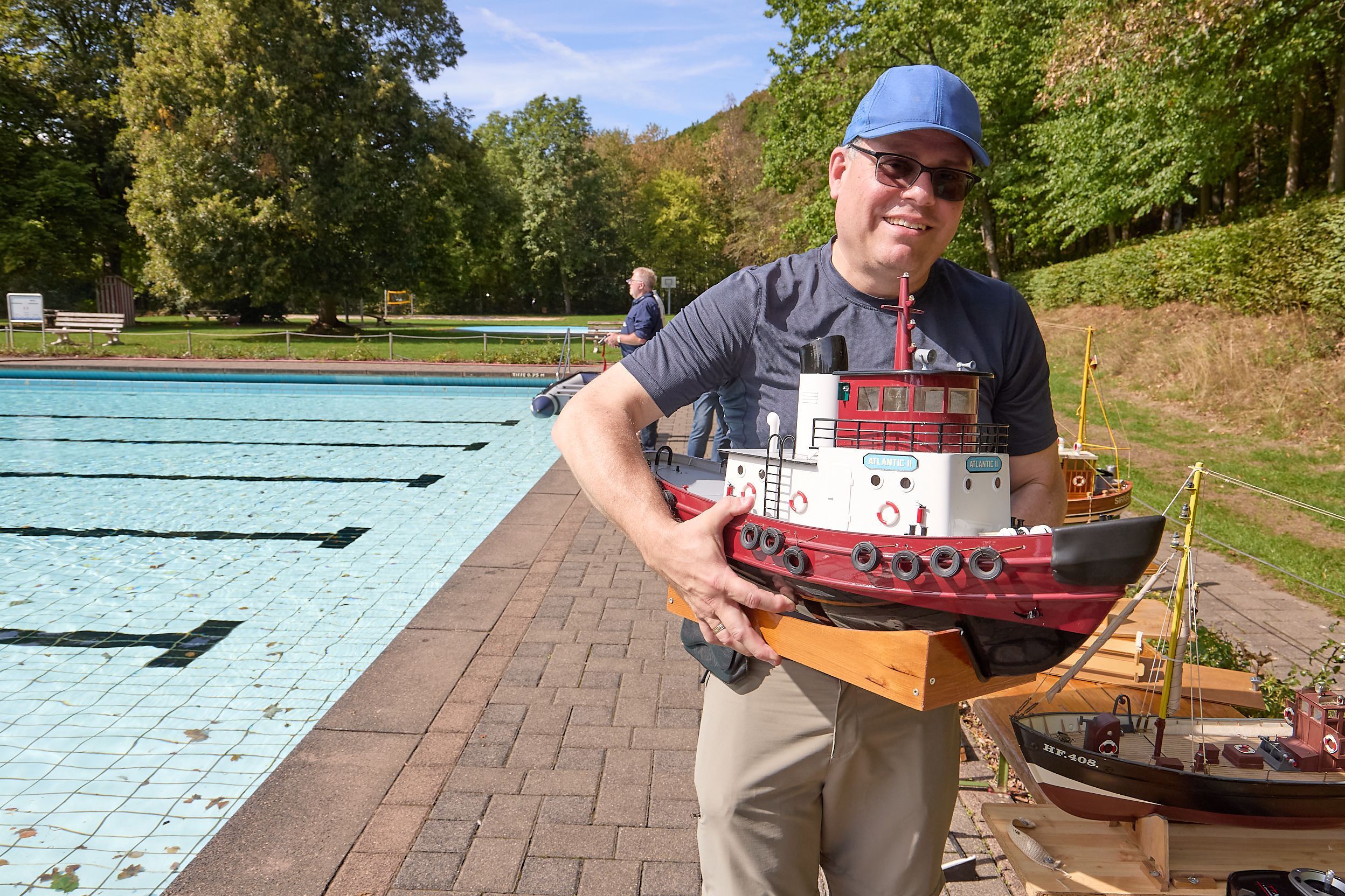 Stefan Irmen steht mit einem großen Modellboot neben dem Becken des Gemünder Rosenbads.