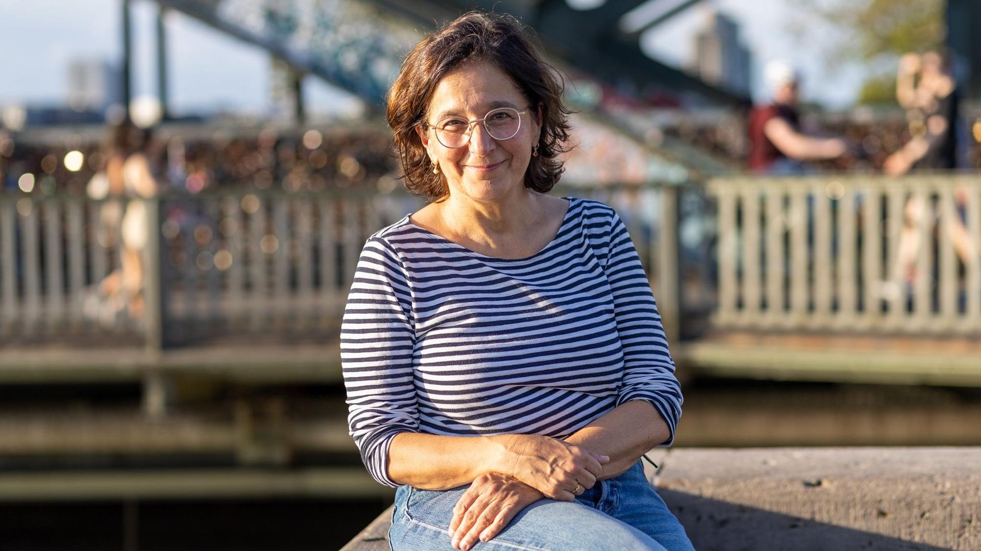 Eine Frau im gestreiften Oberteil lächelt in die Kamera.