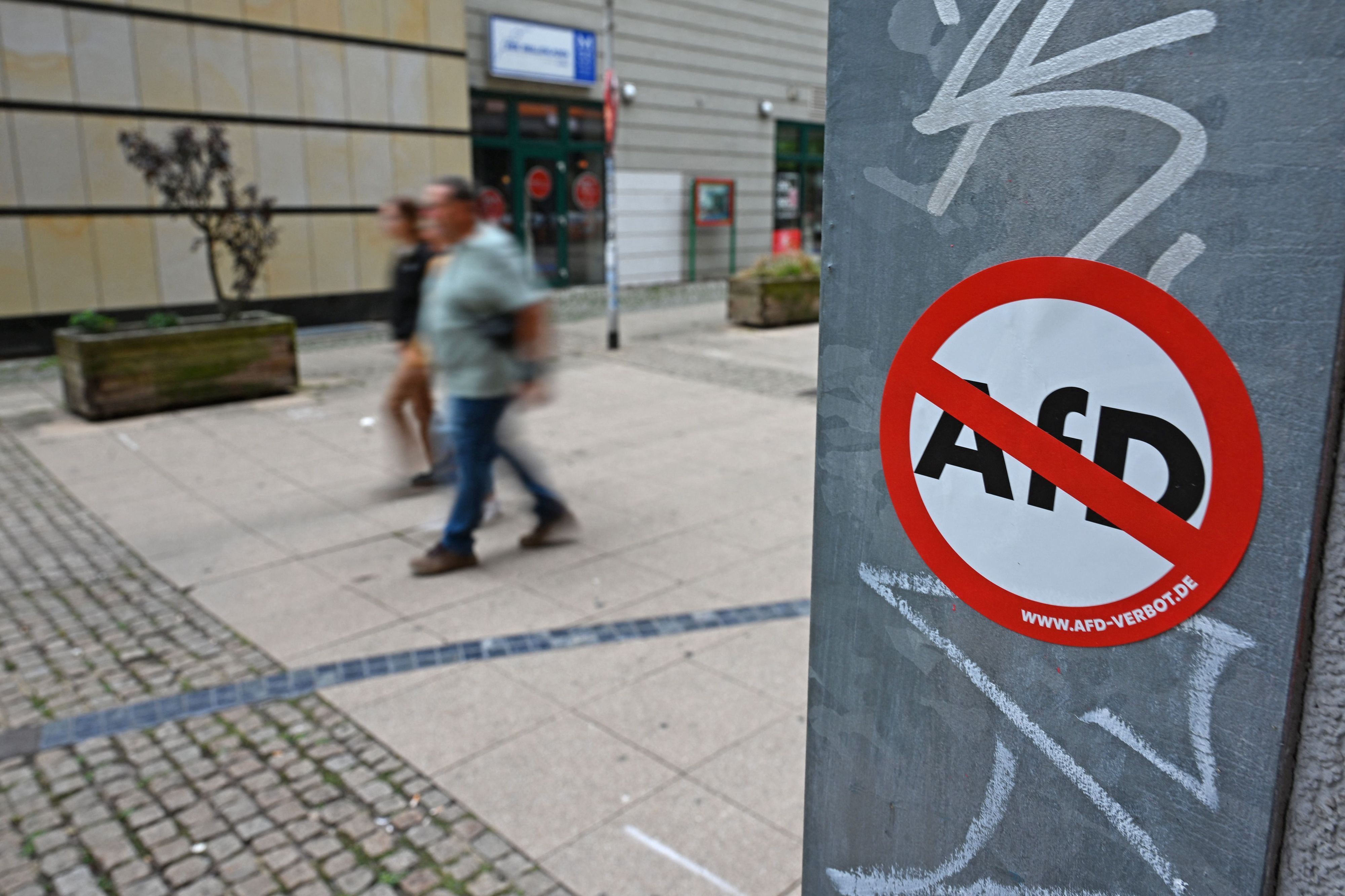 Ein Aufkleber mit der Aufschrift „www.AfD-Verbot.de“ hängt an einem Masten.